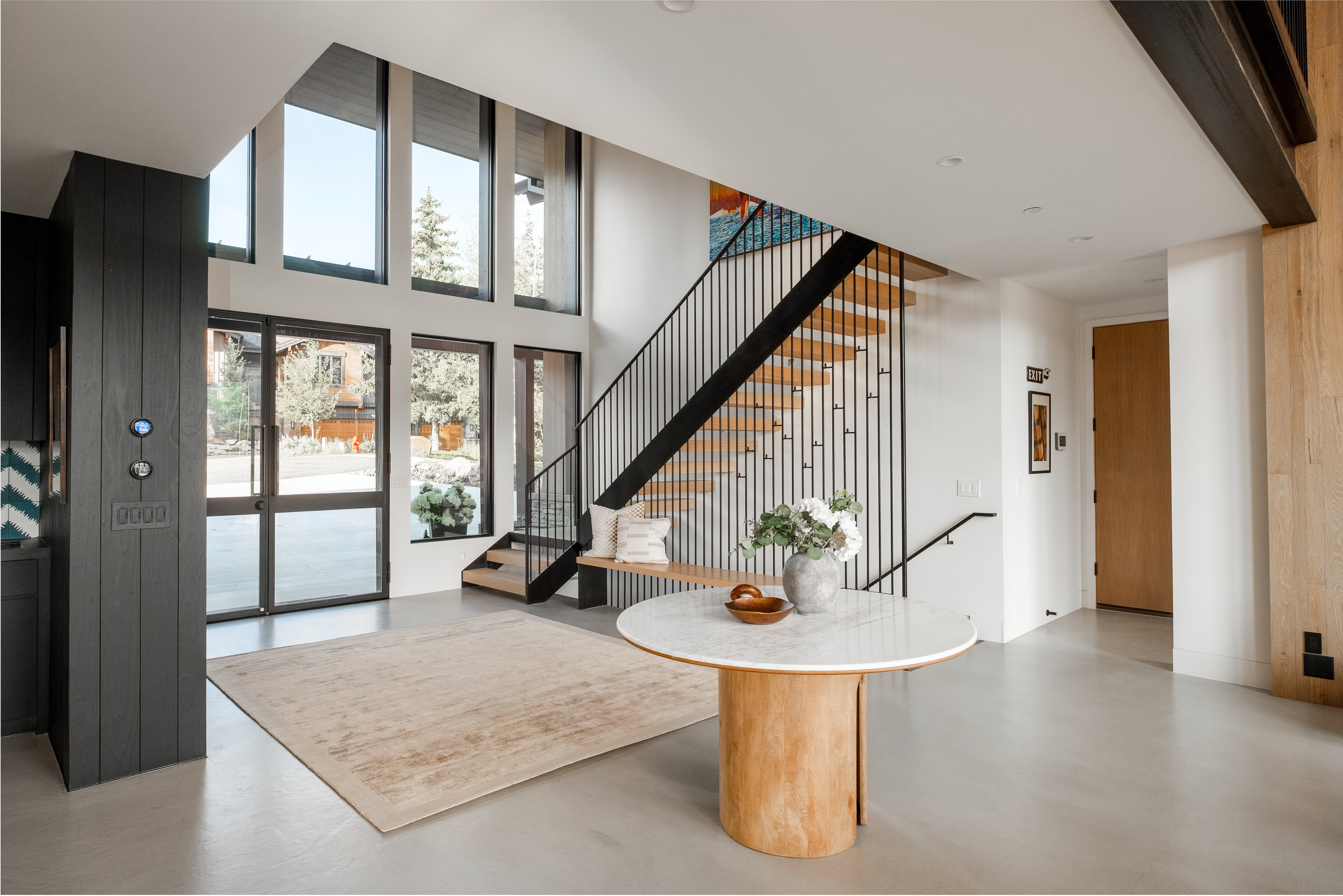 Two-story foyer featuring expansive windows, a floating staircase with black vertical balusters, and light wood stair treads