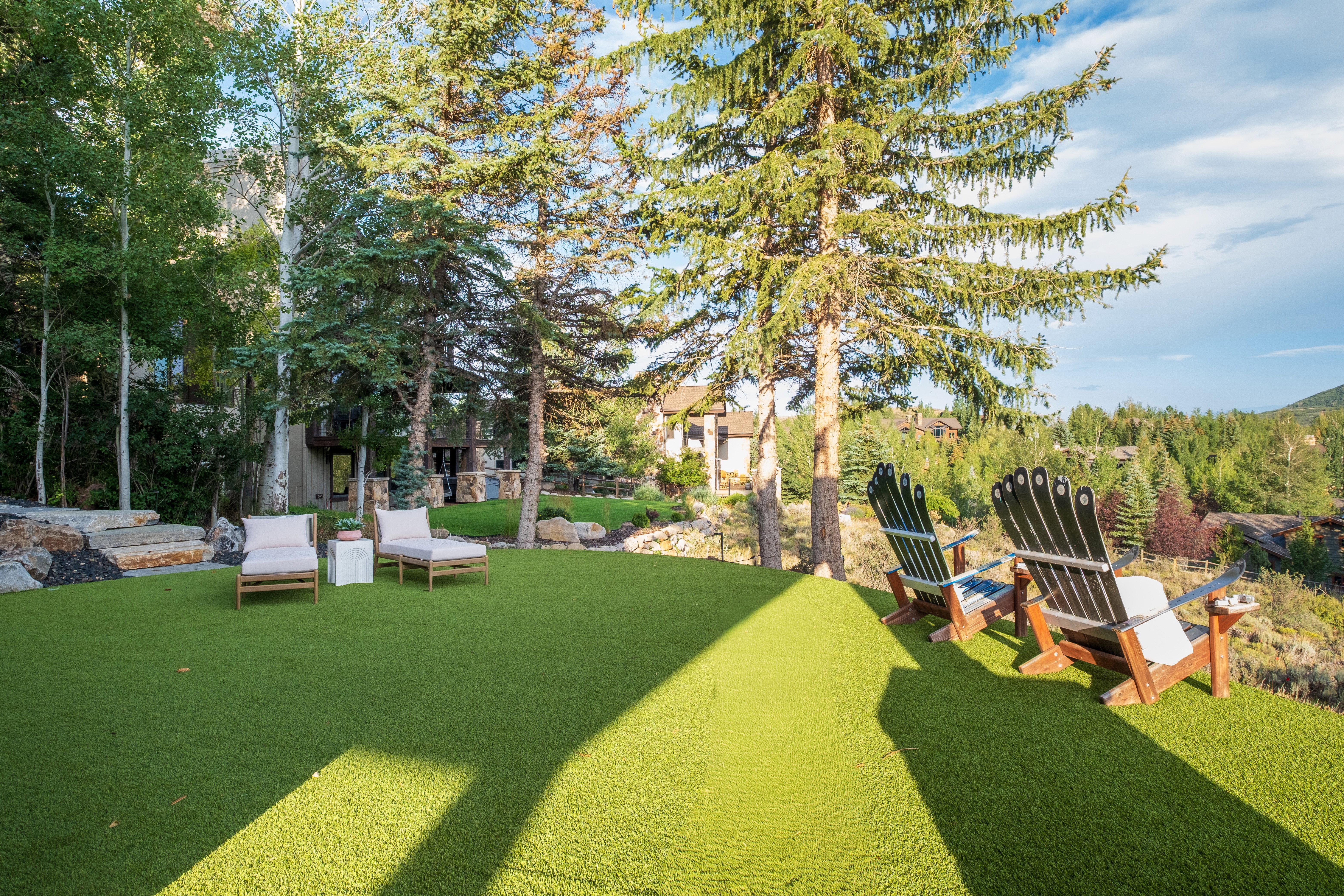 Expansive turf lawn featuring mature evergreen trees and a terraced rock garden