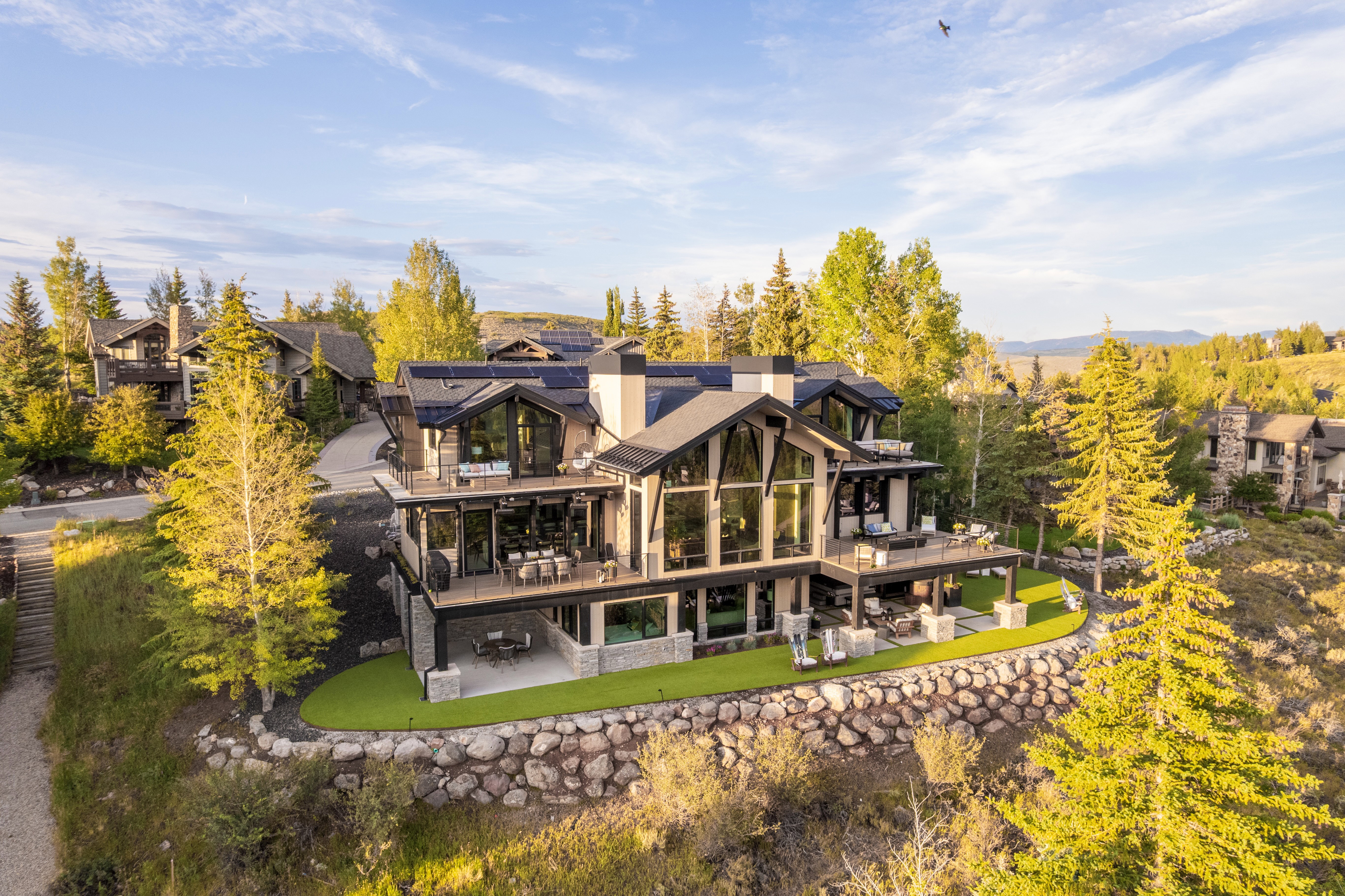 Contemporary mountain-style residence featuring a multi-level design with extensive glasswork and dark-framed windows