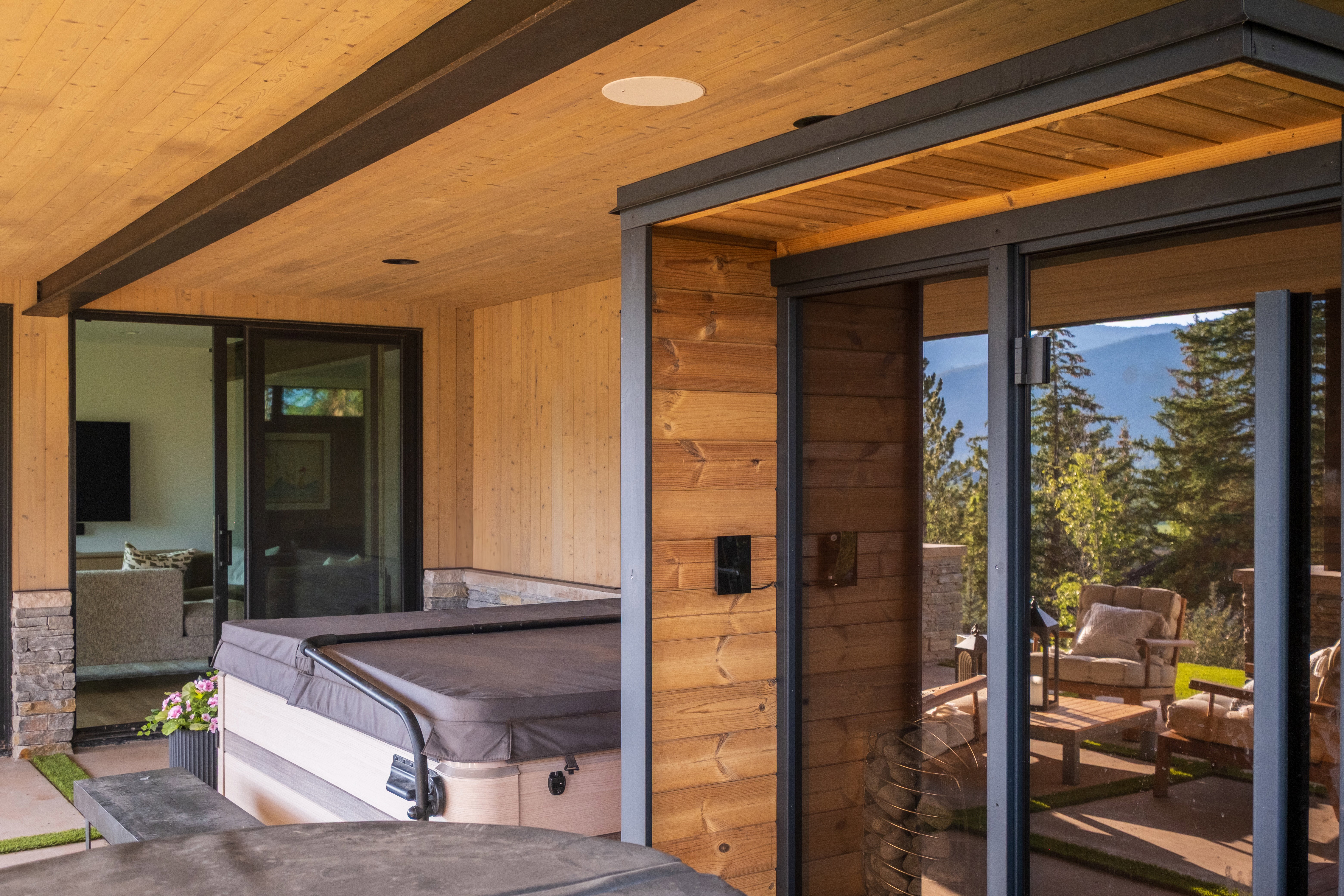 Covered patio with integrated spa, wood-paneled ceiling, exposed structural beams, and sliding glass doors