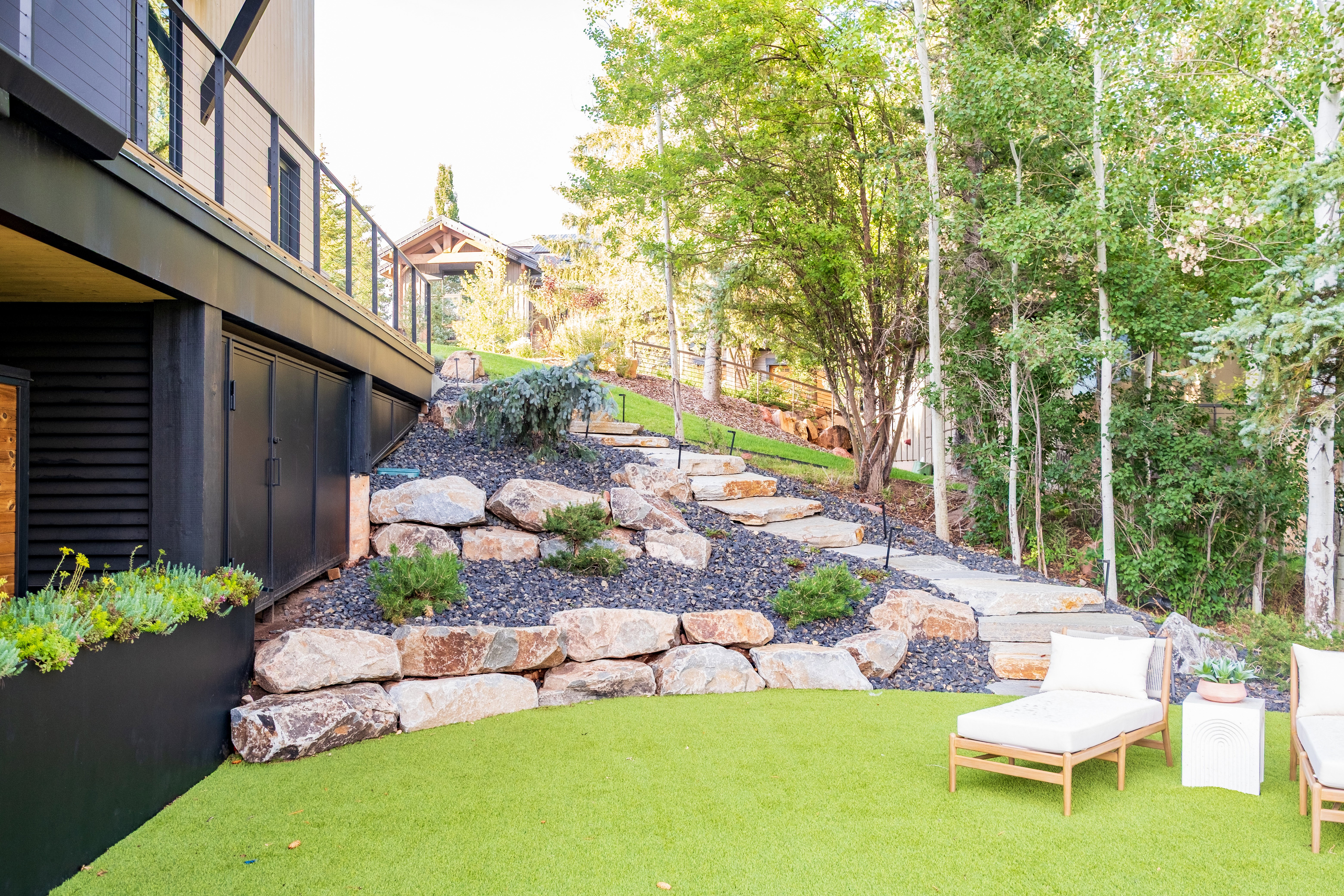 Backyard featuring a stone retaining wall, terraced landscaping with integrated stone steps, and a lush green lawn