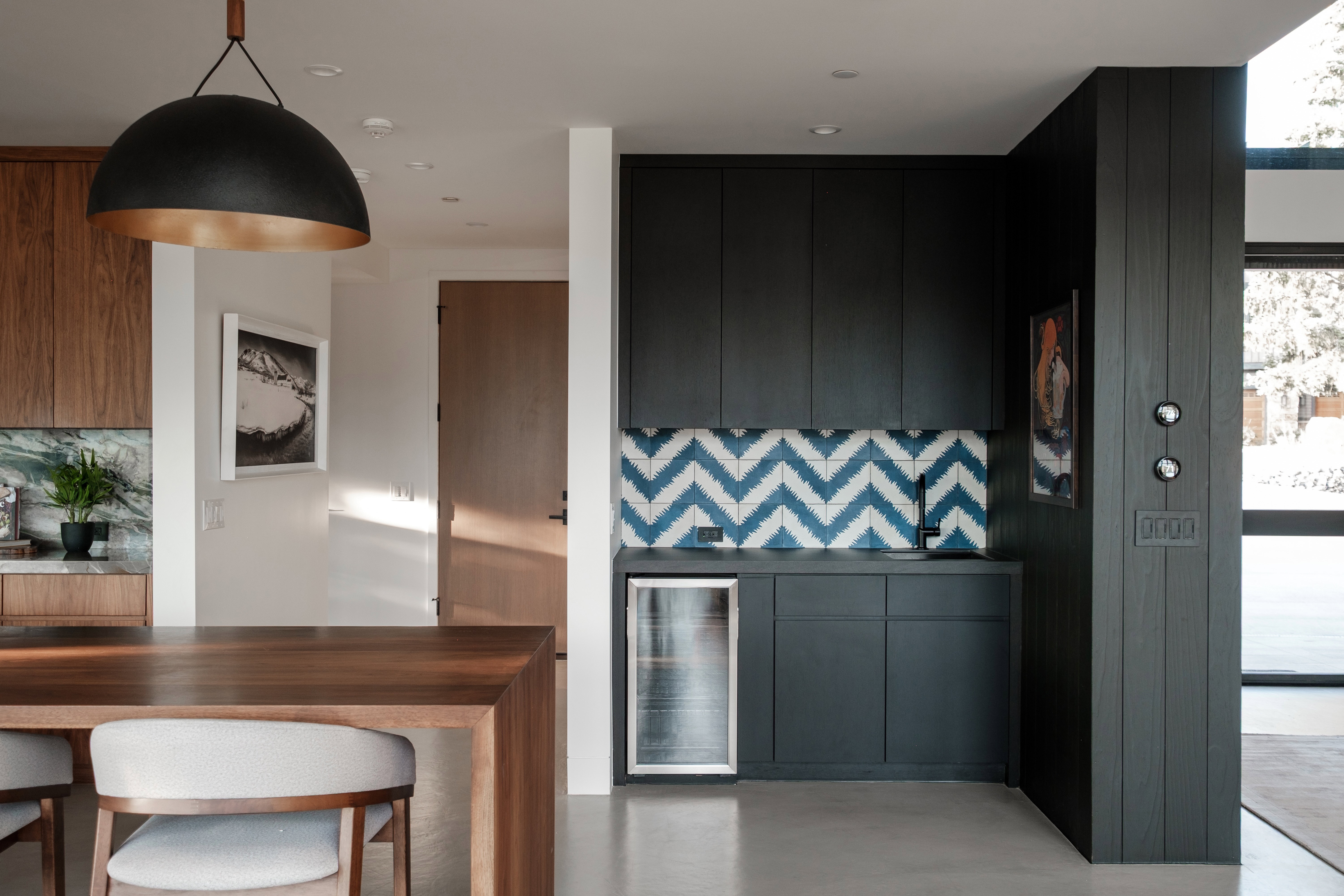 Integrated wet bar featuring a built-in beverage refrigerator, patterned backsplash, and dark cabinetry