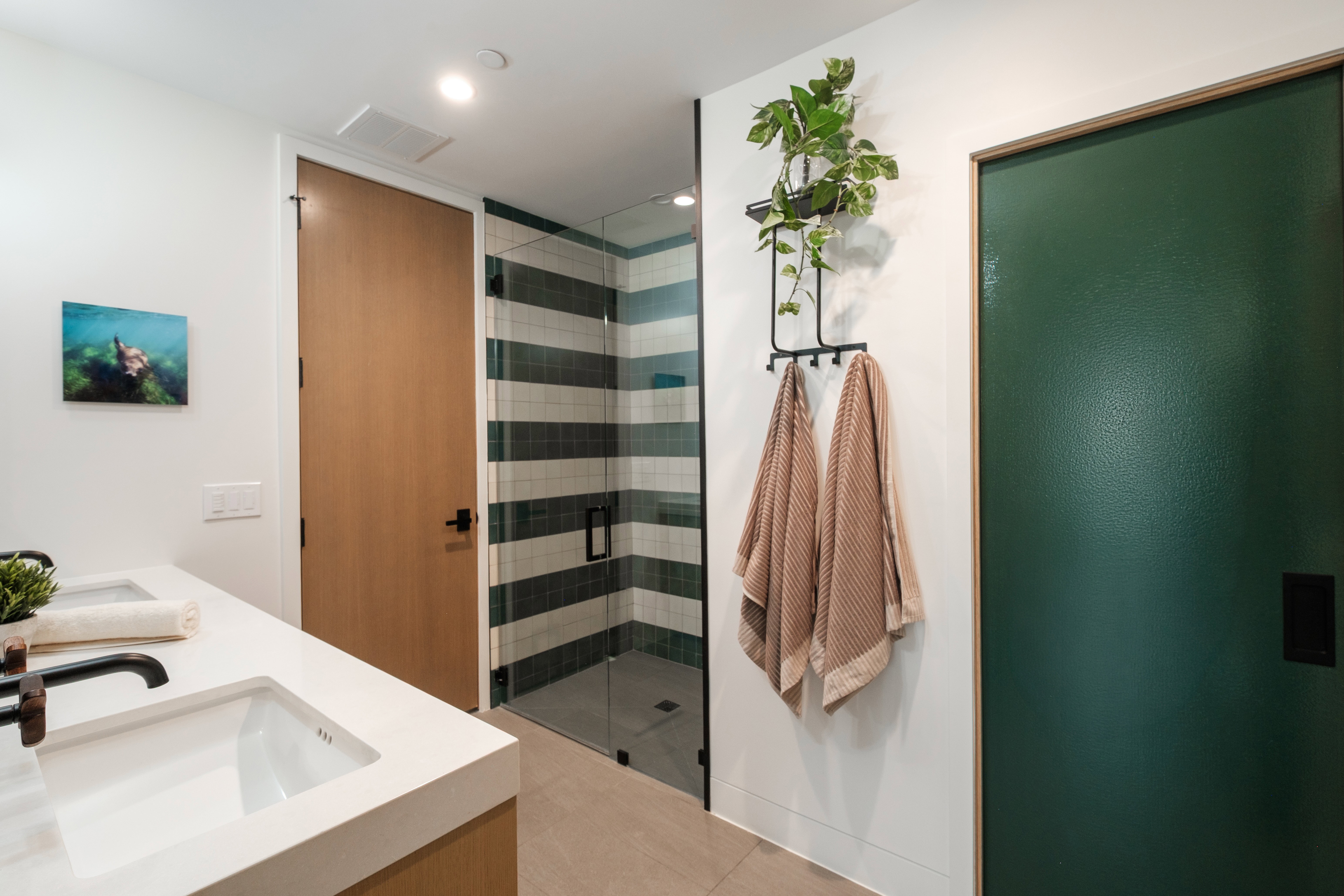 Contemporary bathroom featuring a spacious glass-enclosed shower with striped tile, double vanity with integrated sinks, and matte black fixtures