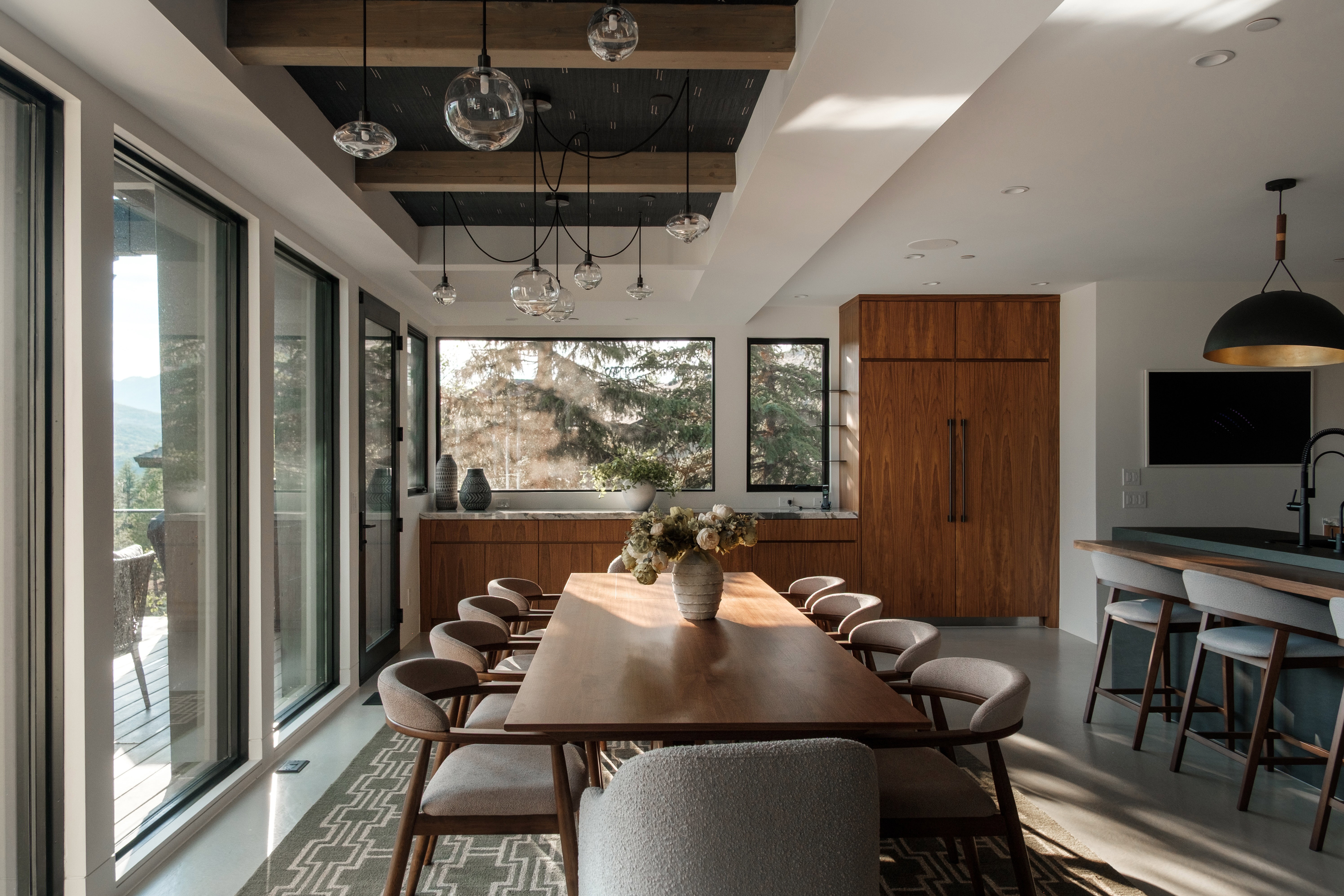 Modern dining area featuring a dark wood-finish dining table, recessed lighting, and an array of pendant light fixtures