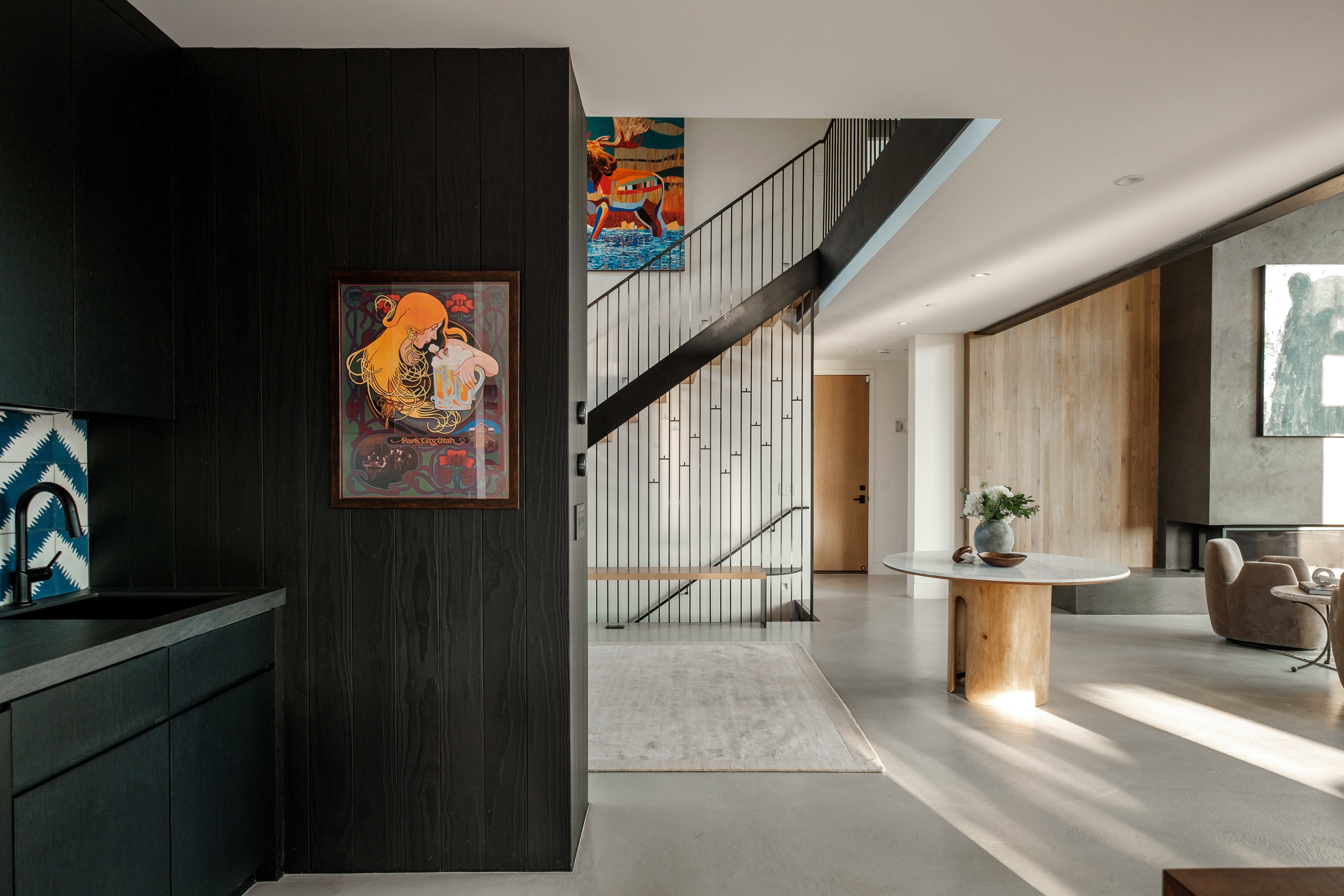Open-concept living space with concrete flooring, a floating staircase featuring metal railings, and a built-in fireplace with a concrete surround