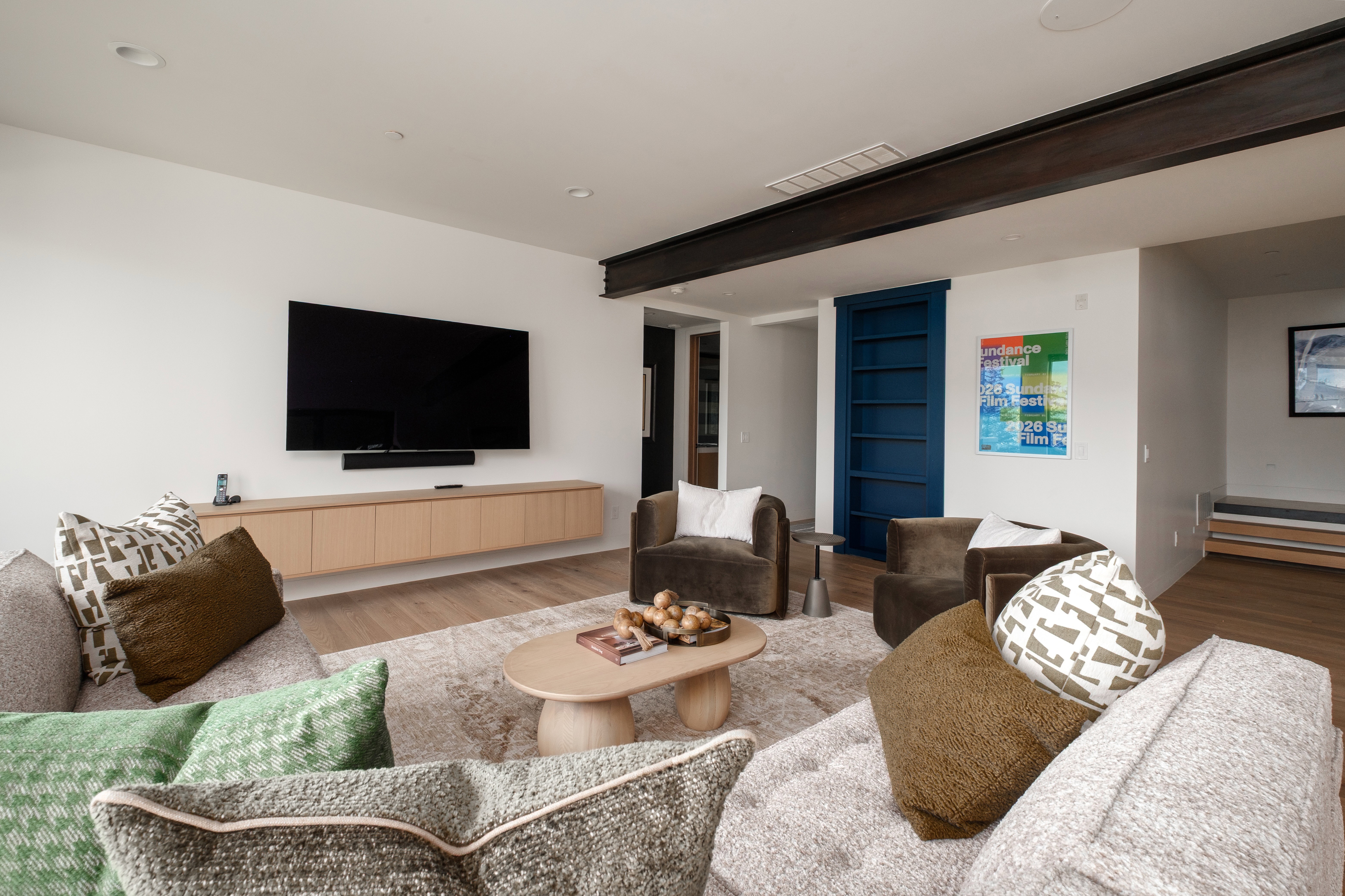 Spacious living area featuring a floating media console, large wall-mounted television, and wood-finish flooring