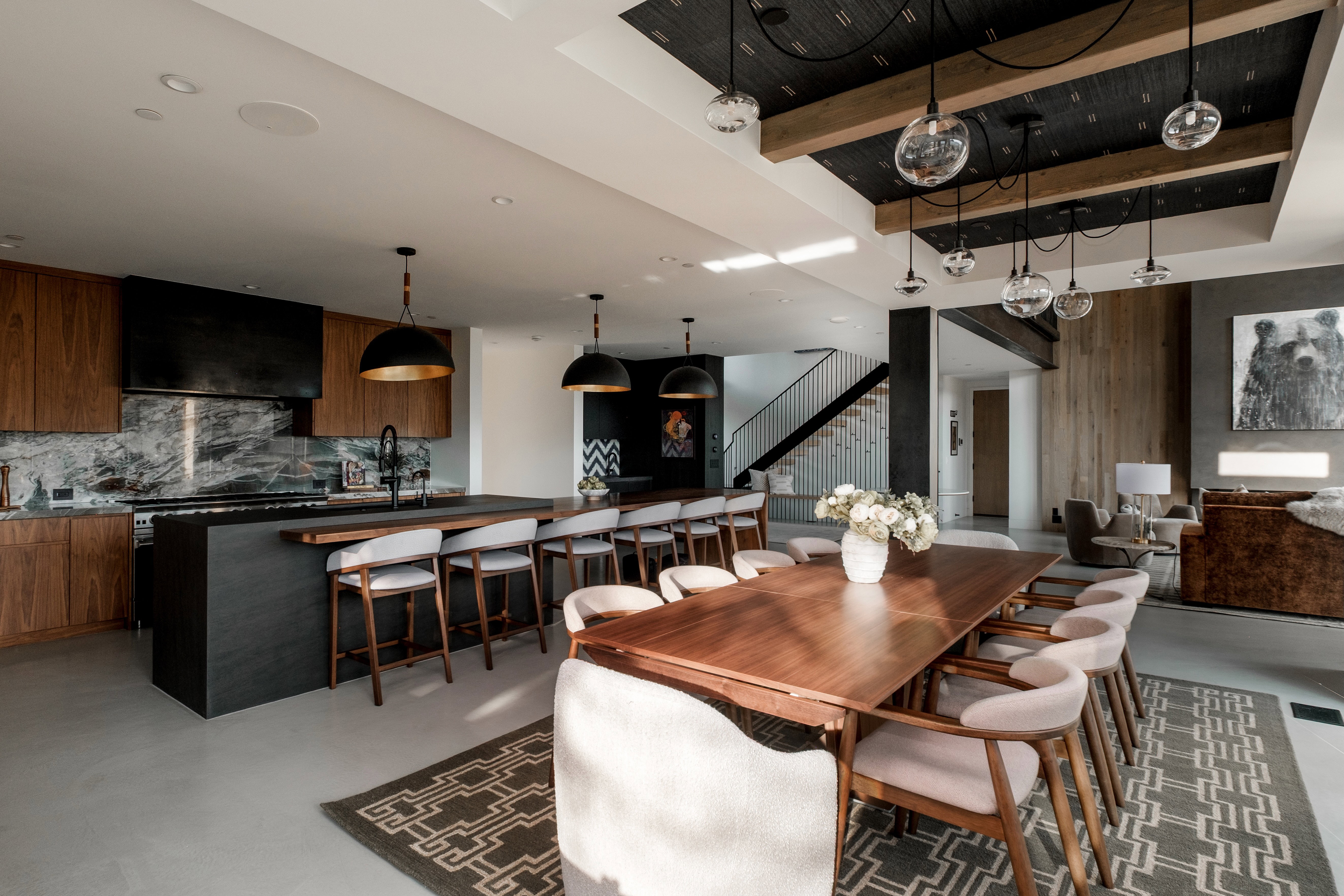 Open-concept dining and kitchen space featuring a long wood-finish dining table and a multi-pendant ceiling light fixture