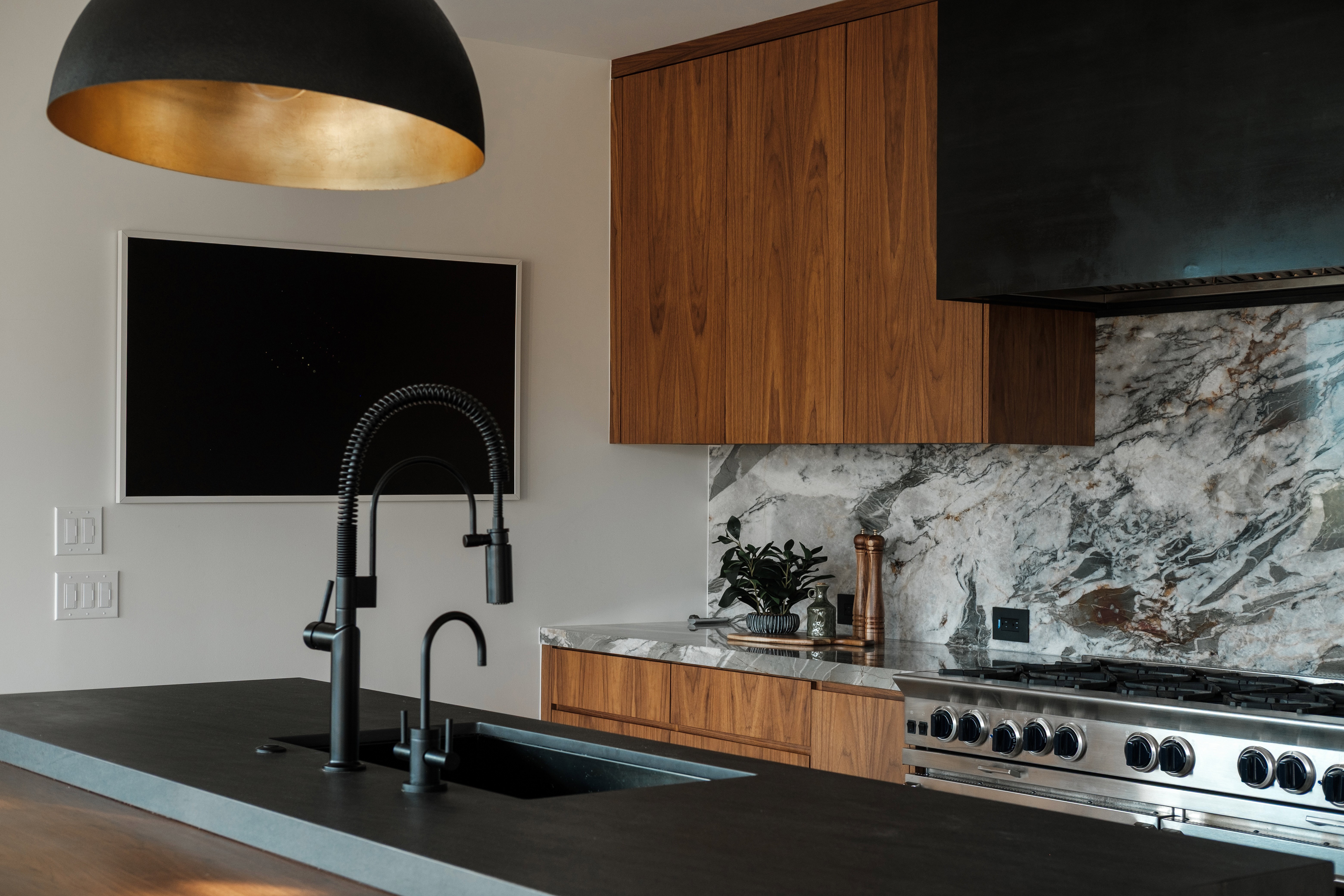 Kitchen featuring a black sink with a matte black gooseneck faucet and a complementary smaller faucet, set into a dark countertop