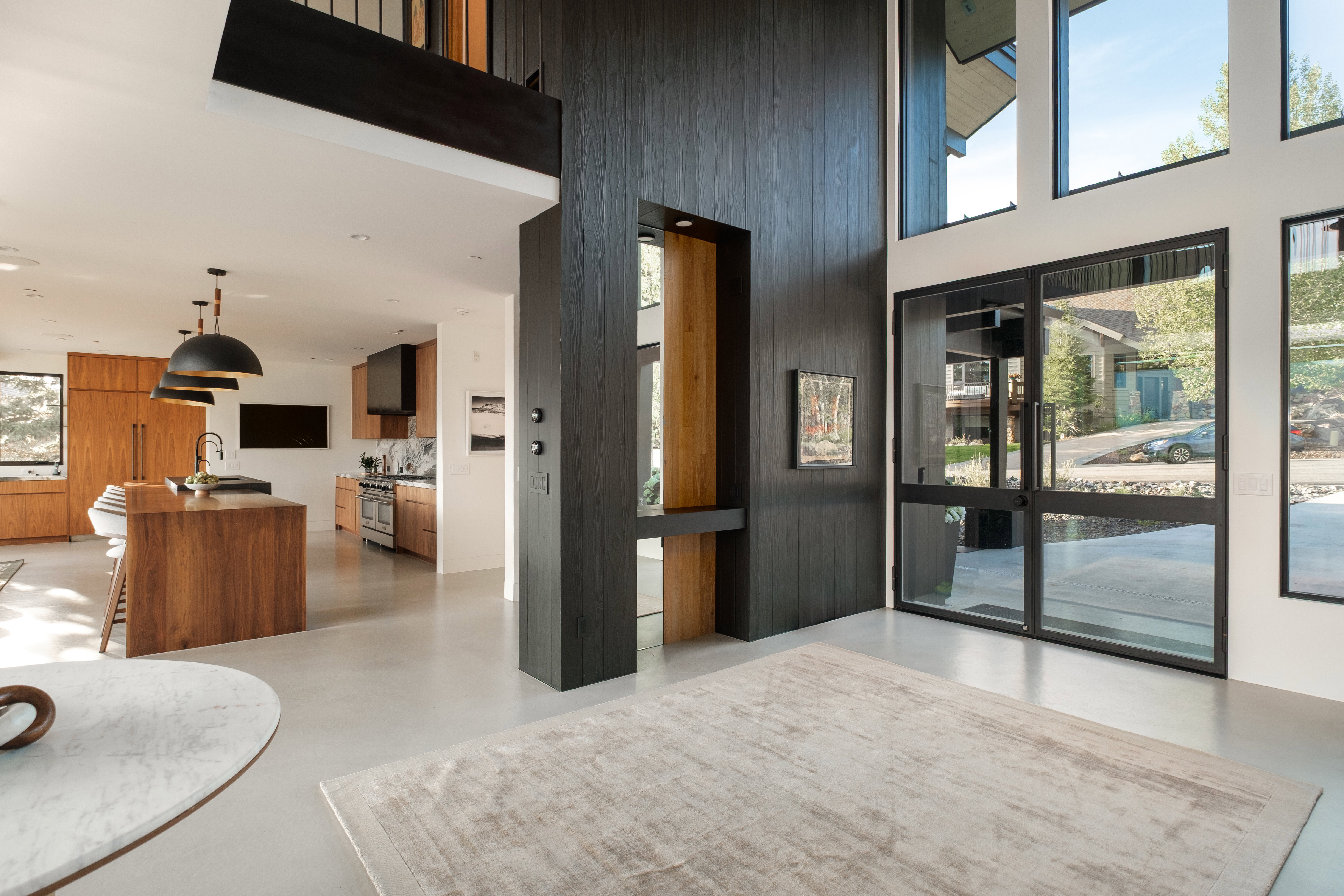 Two-story entry featuring black wood-paneled walls and large black-framed windows