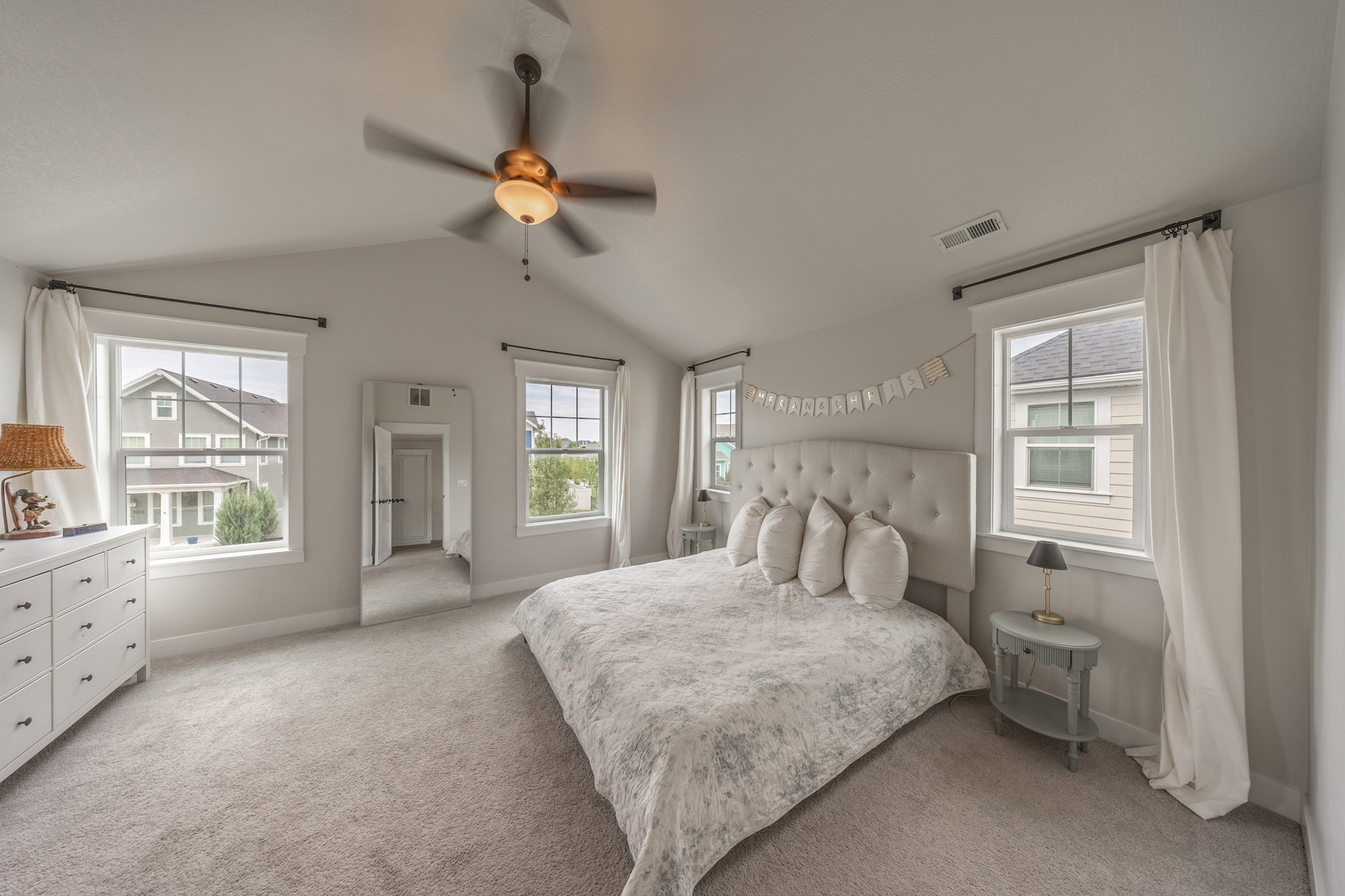 Carpeted interior space featuring a vaulted ceiling with a ceiling fan
