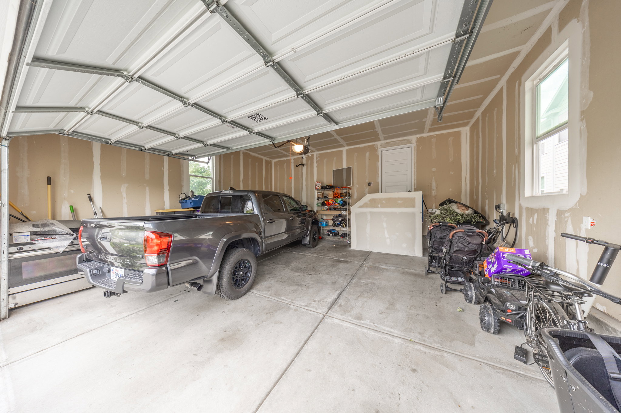 Two-car garage featuring a concrete floor, an overhead garage door, and two windows providing natural light