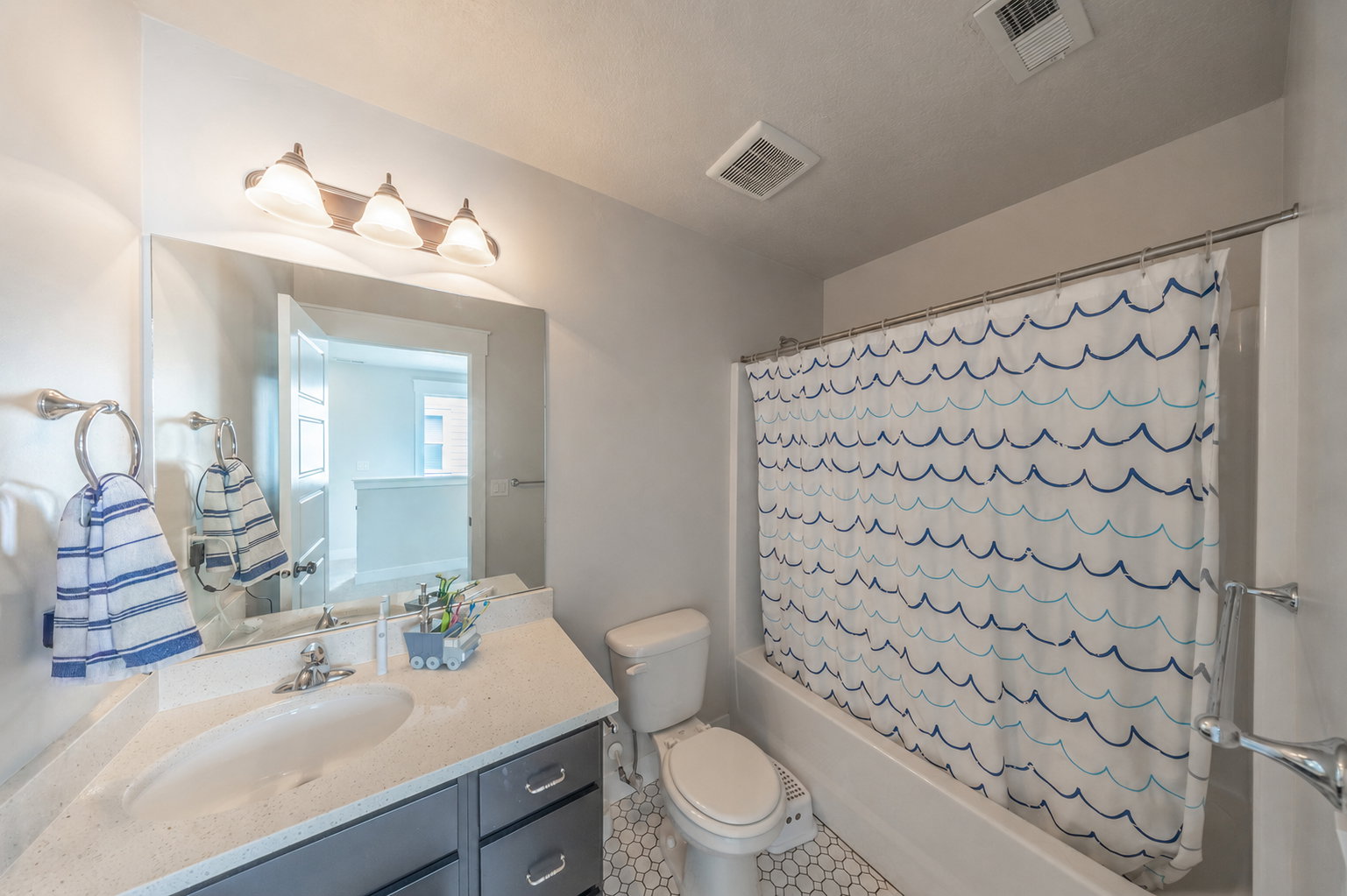 Bathroom featuring a single vanity with stone-finish countertop, undermount sink, and dark cabinetry