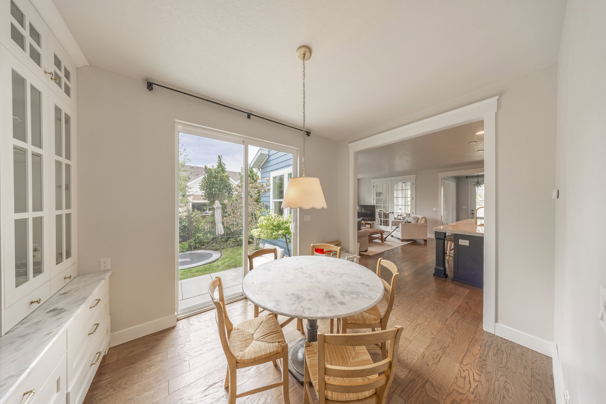 Dining area featuring wood-finish flooring and a built-in hutch with glass-front cabinetry and a stone countertop