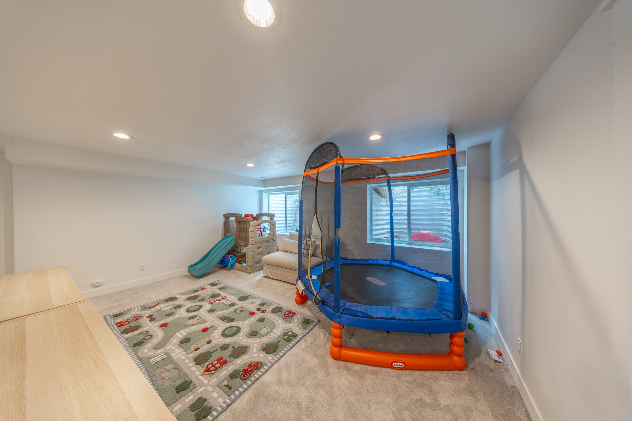 Expansive recreation space featuring recessed lighting, light-toned carpeting, and a built-in window with horizontal blinds