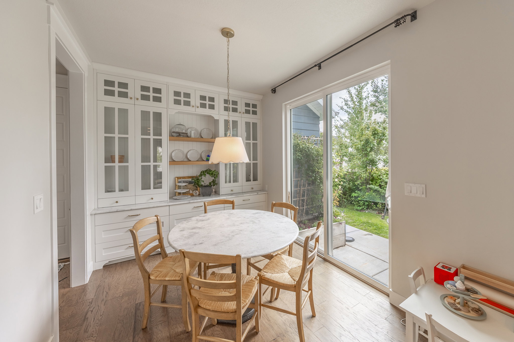Built-in white cabinetry with glass-front uppers and quartz countertops, featuring wood-finish flooring