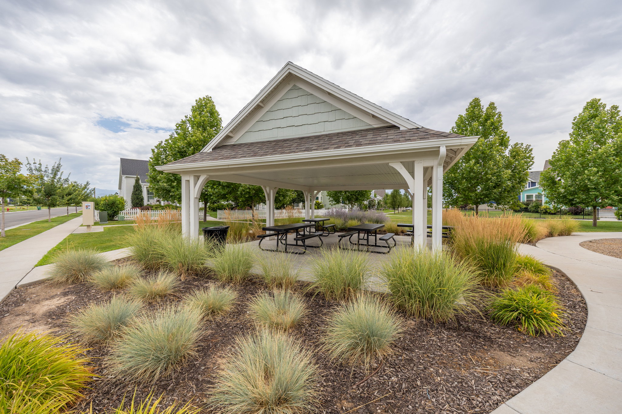 Covered gazebo with decorative gables, shingled roof, and paved flooring