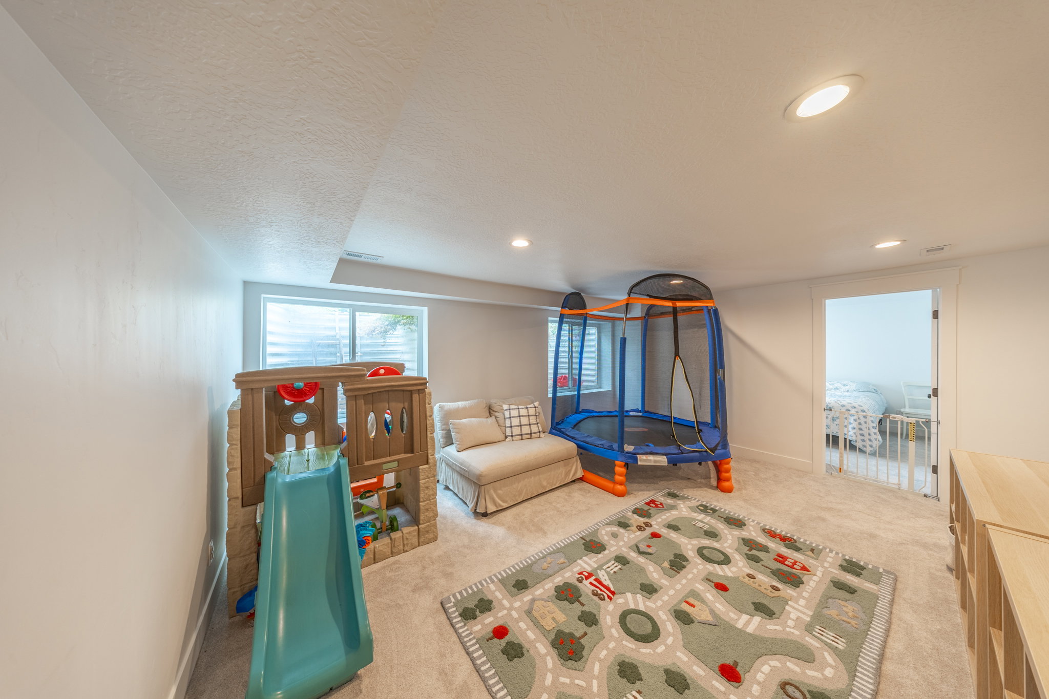 Carpeted recreation room featuring white walls, recessed lighting, and a horizontal window with blinds