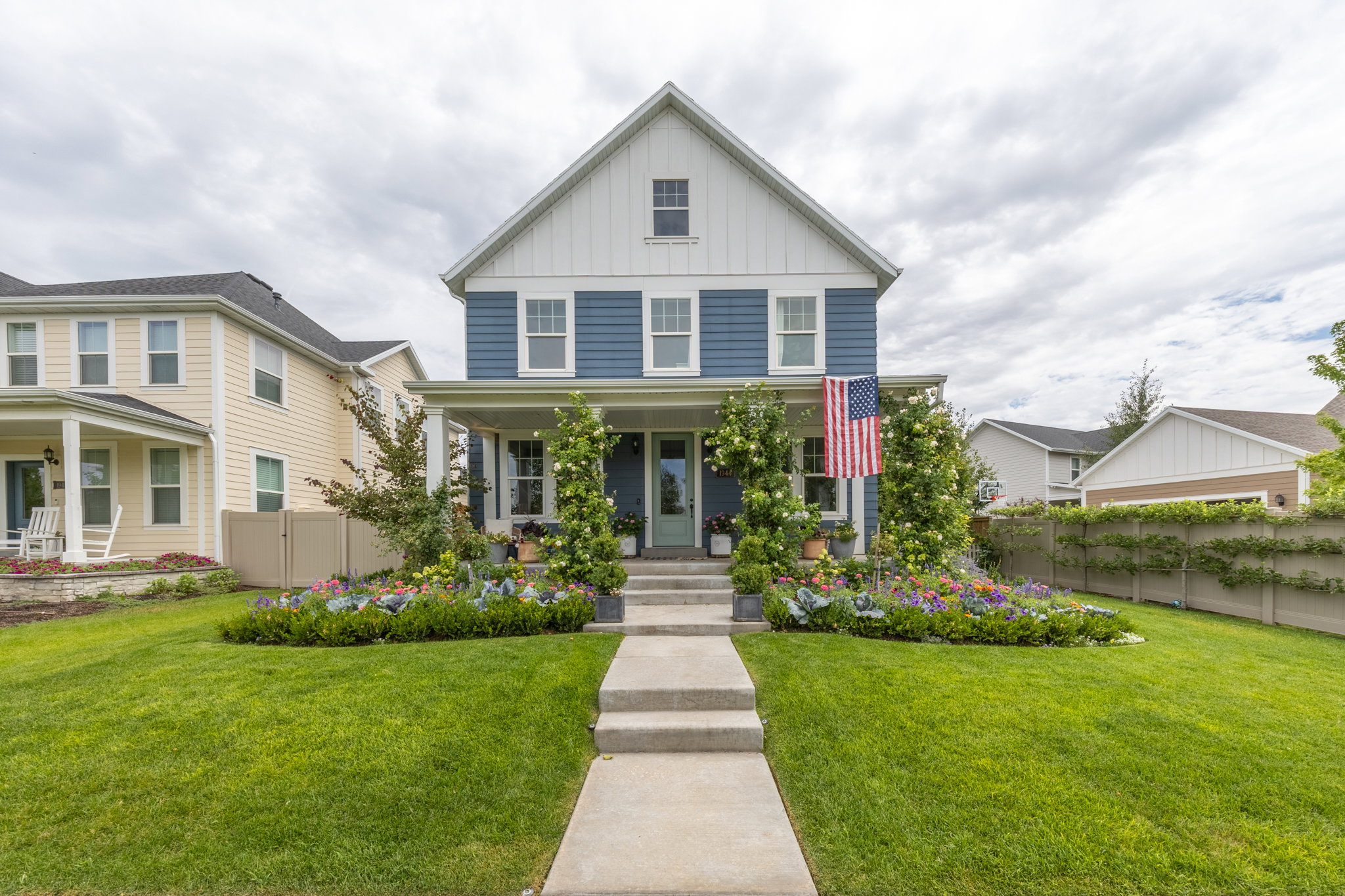 Blue facade home featuring a white gable, white window trim, and dark shutters