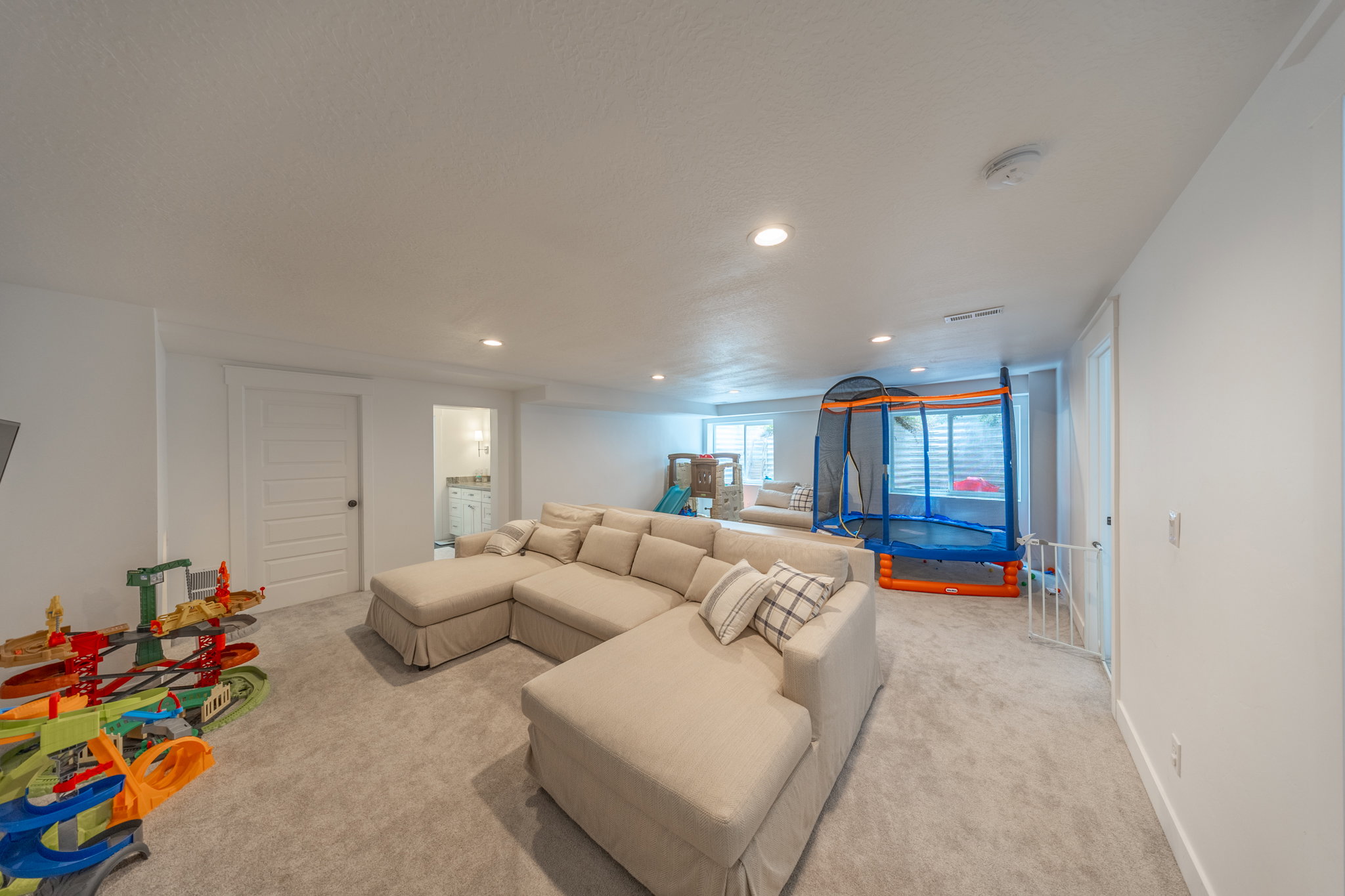 Spacious lower-level area featuring light-toned carpeting, recessed lighting, and white walls