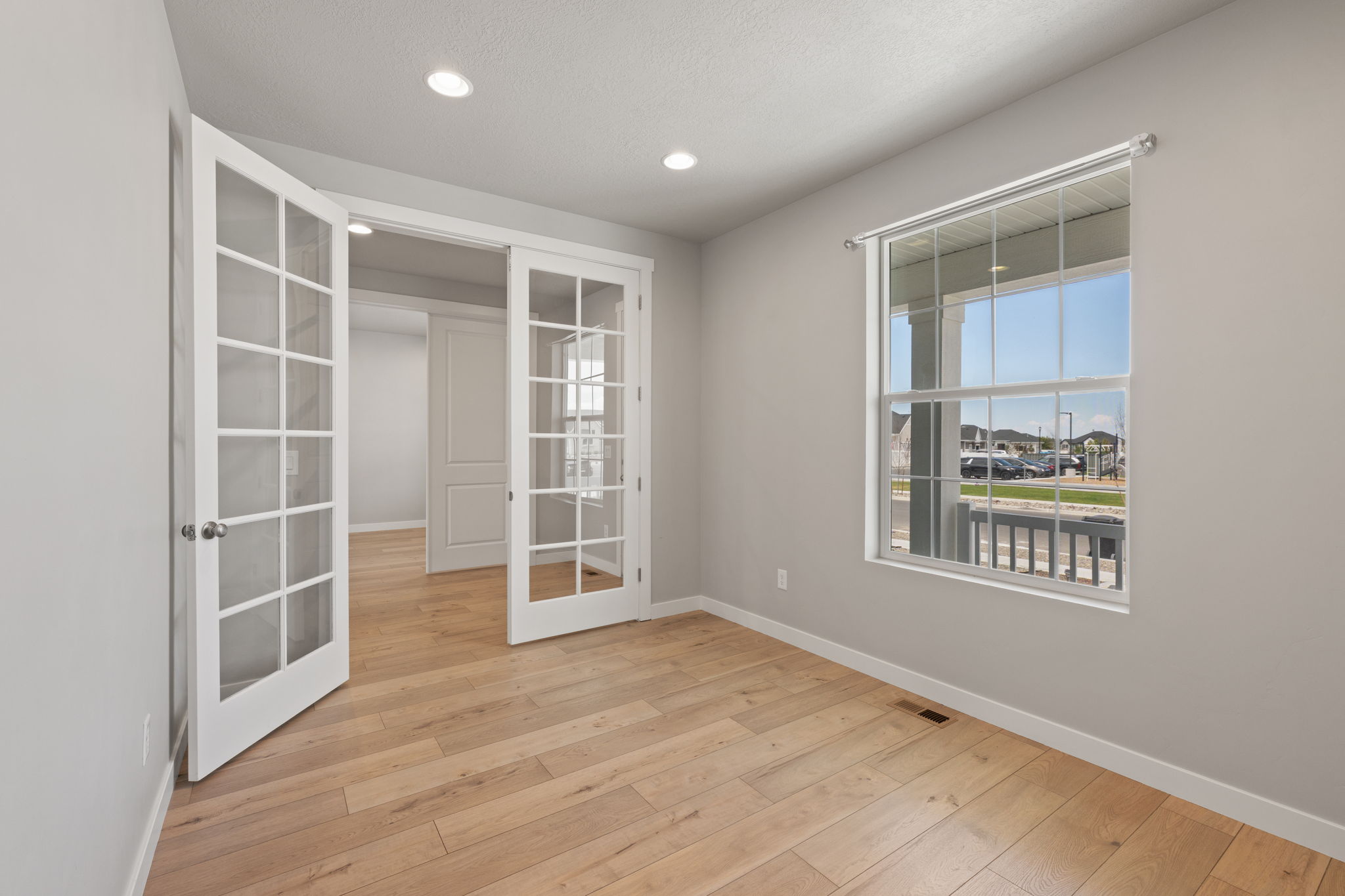Room featuring French doors with glass panes, wood-finish flooring, recessed lighting, and a large window with white trim