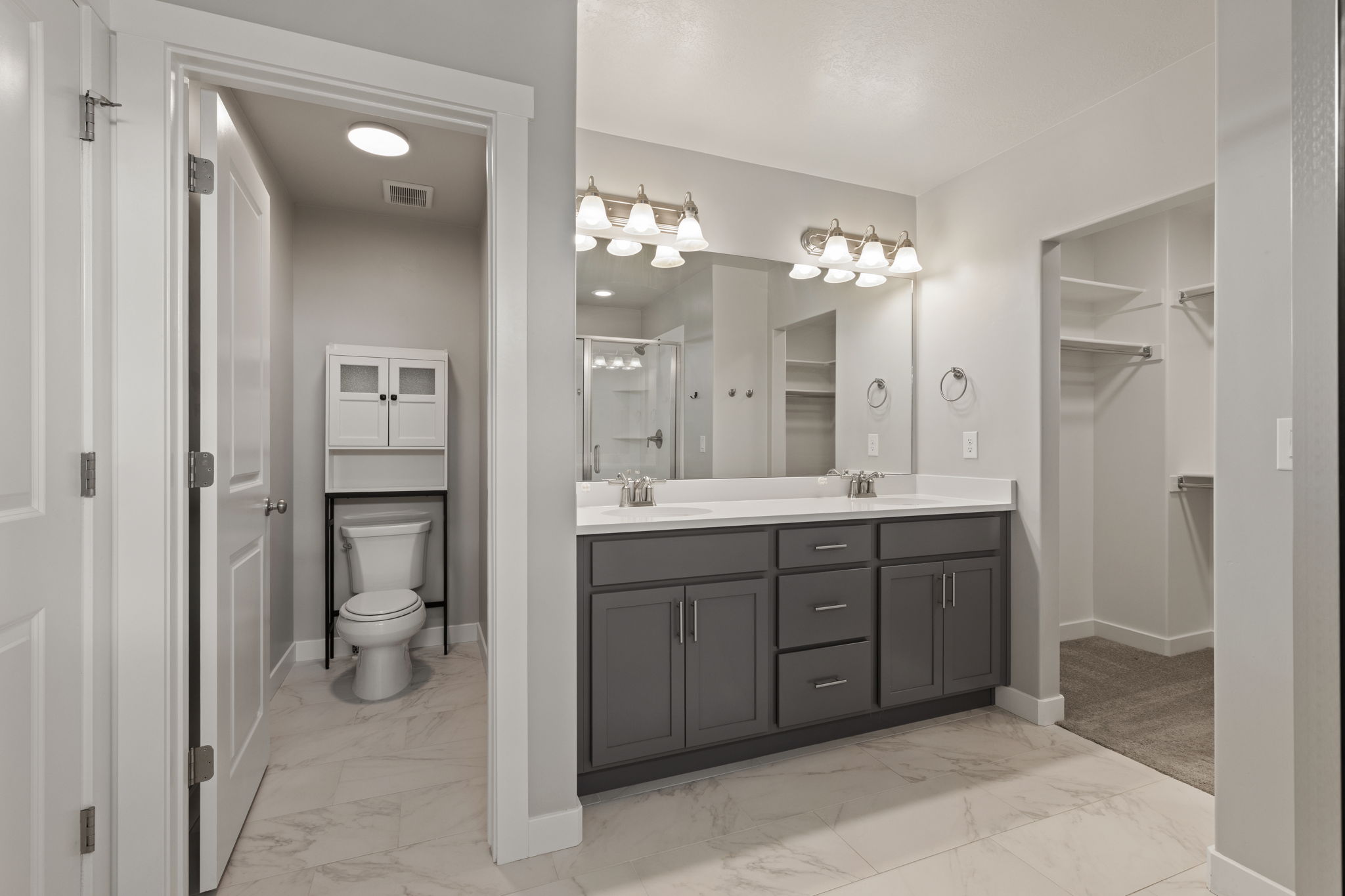 Bathroom featuring a dual vanity with grey cabinetry, white countertops, and brushed nickel fixtures