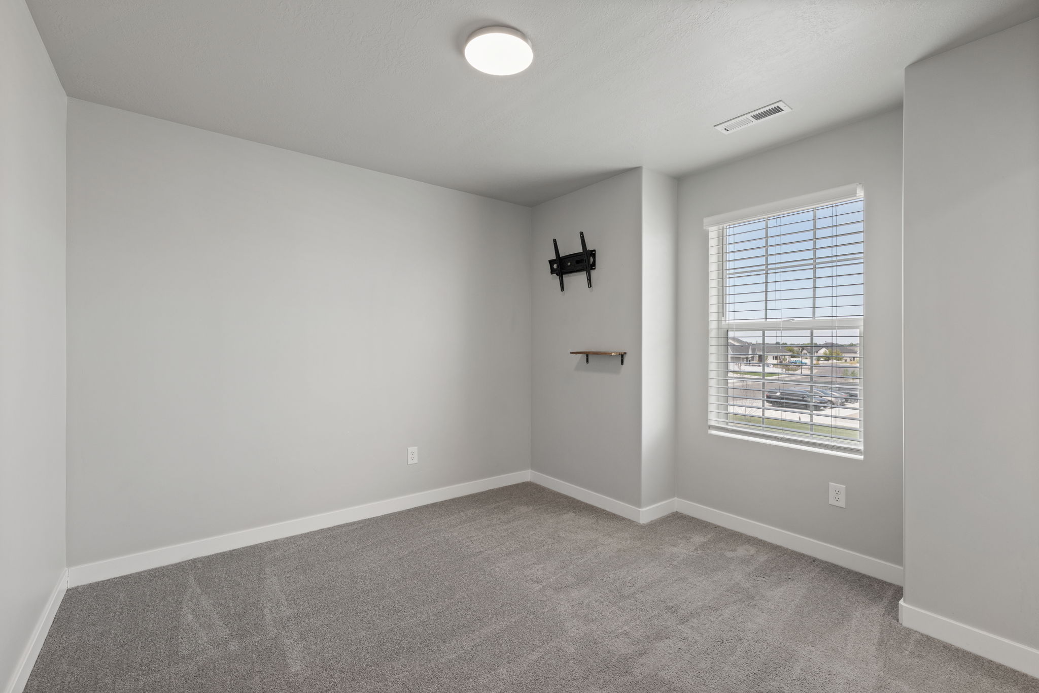 Interior room featuring gray textured carpeting, light gray wall paint, and white baseboards