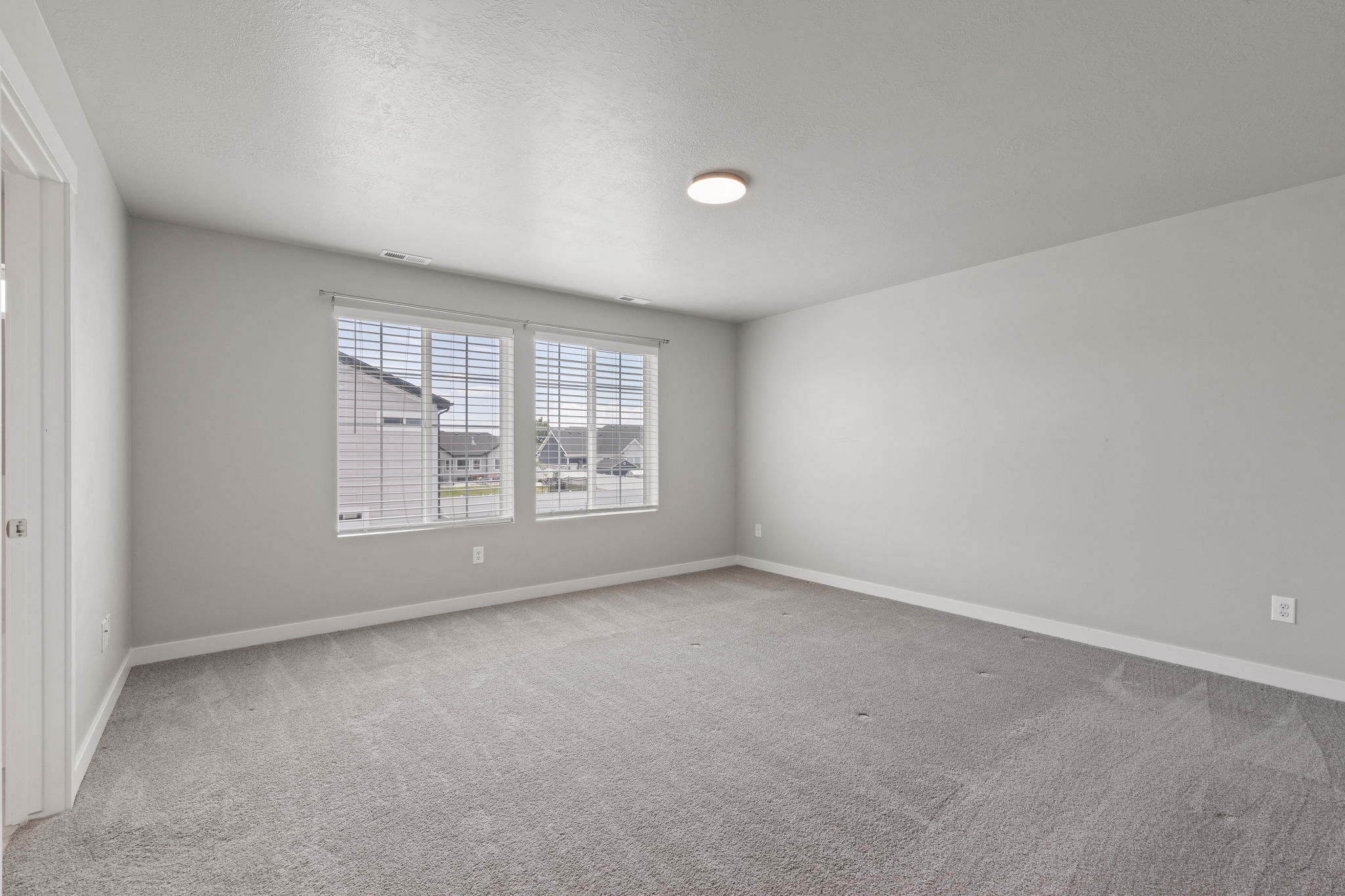 Spacious room featuring gray carpet flooring, light gray wall paint, and white trim