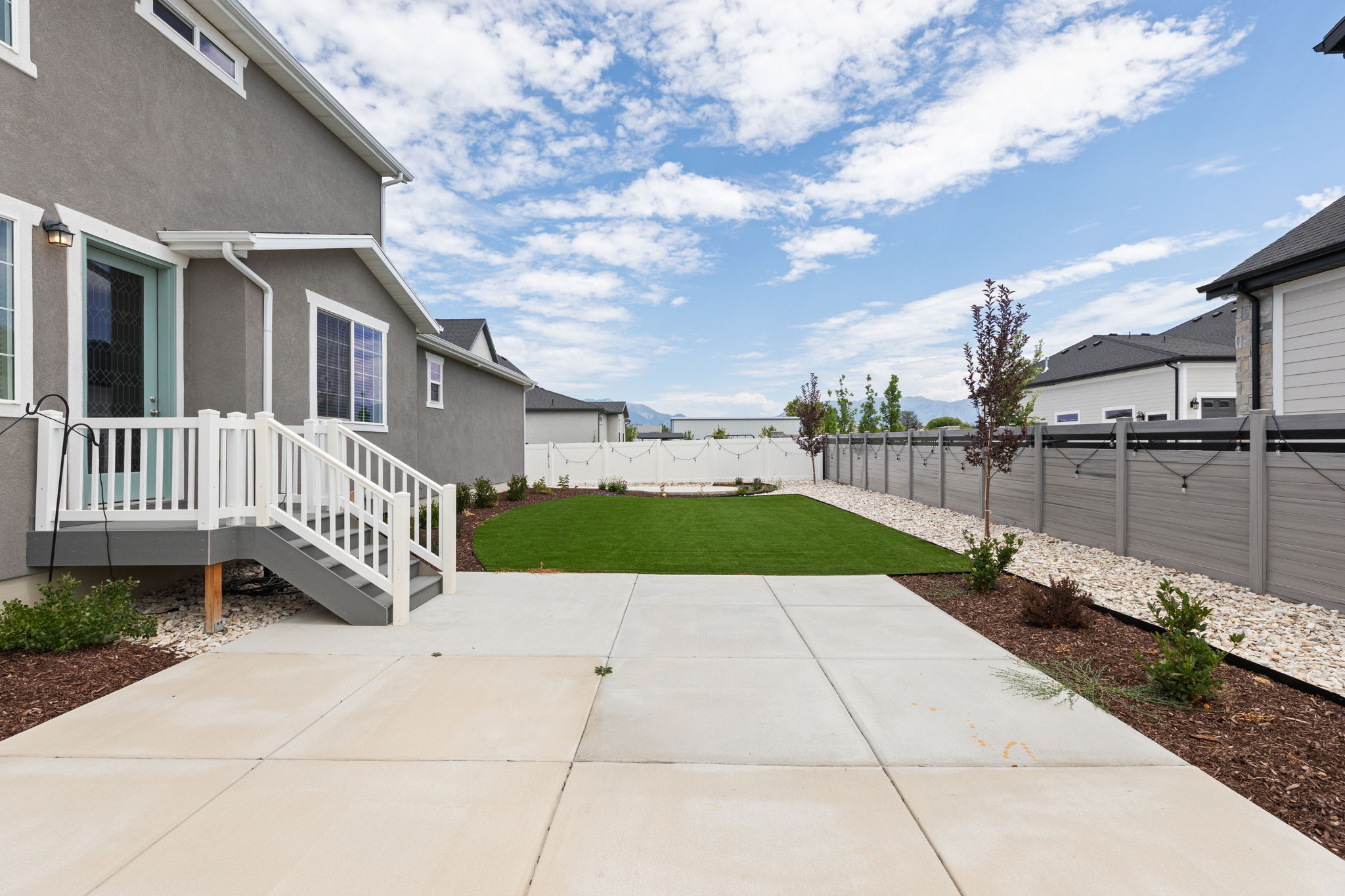 Expansive concrete patio with direct access to a manicured artificial turf lawn