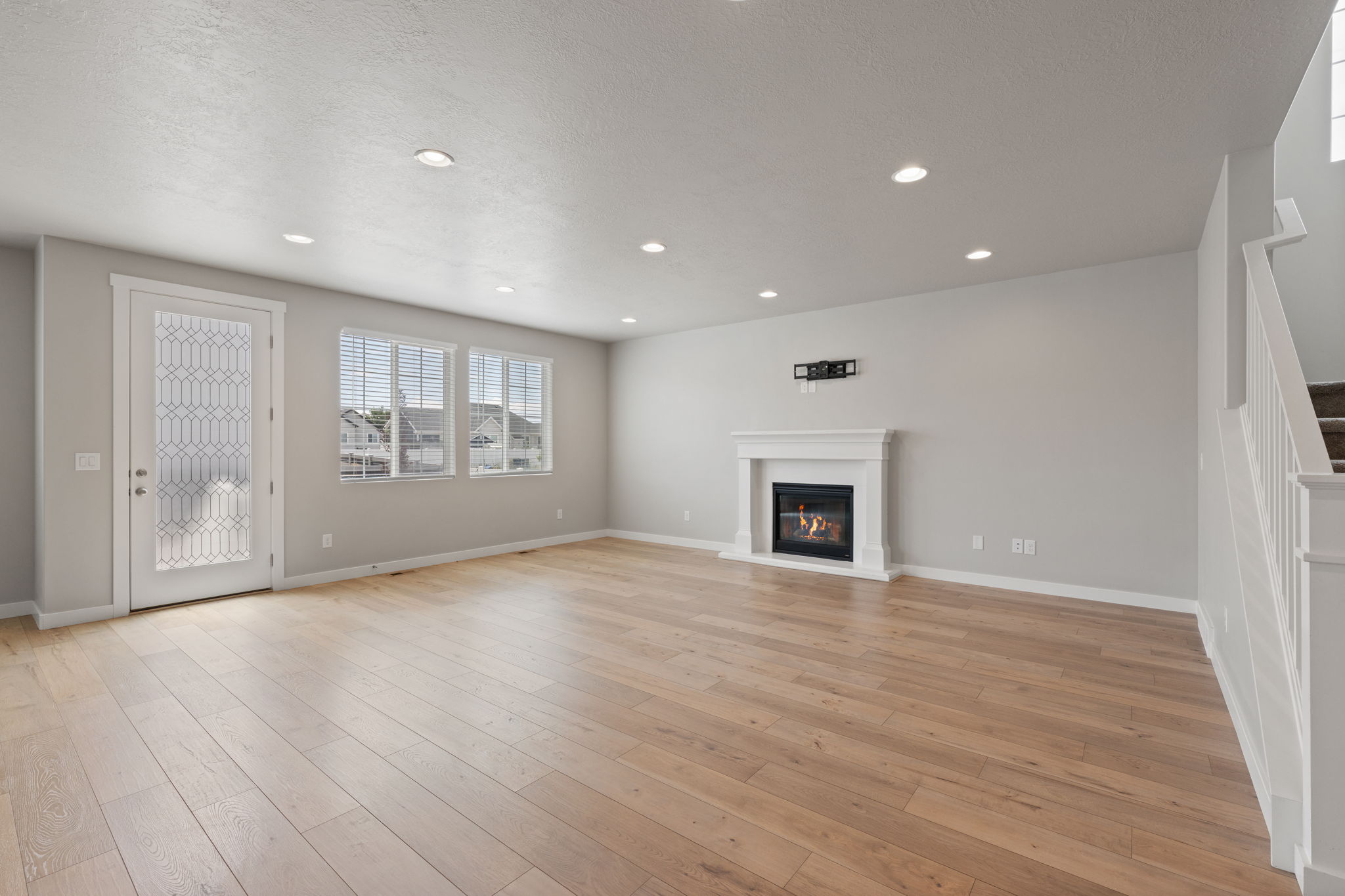 Spacious interior featuring wood-finish flooring, recessed lighting, and a white mantel fireplace