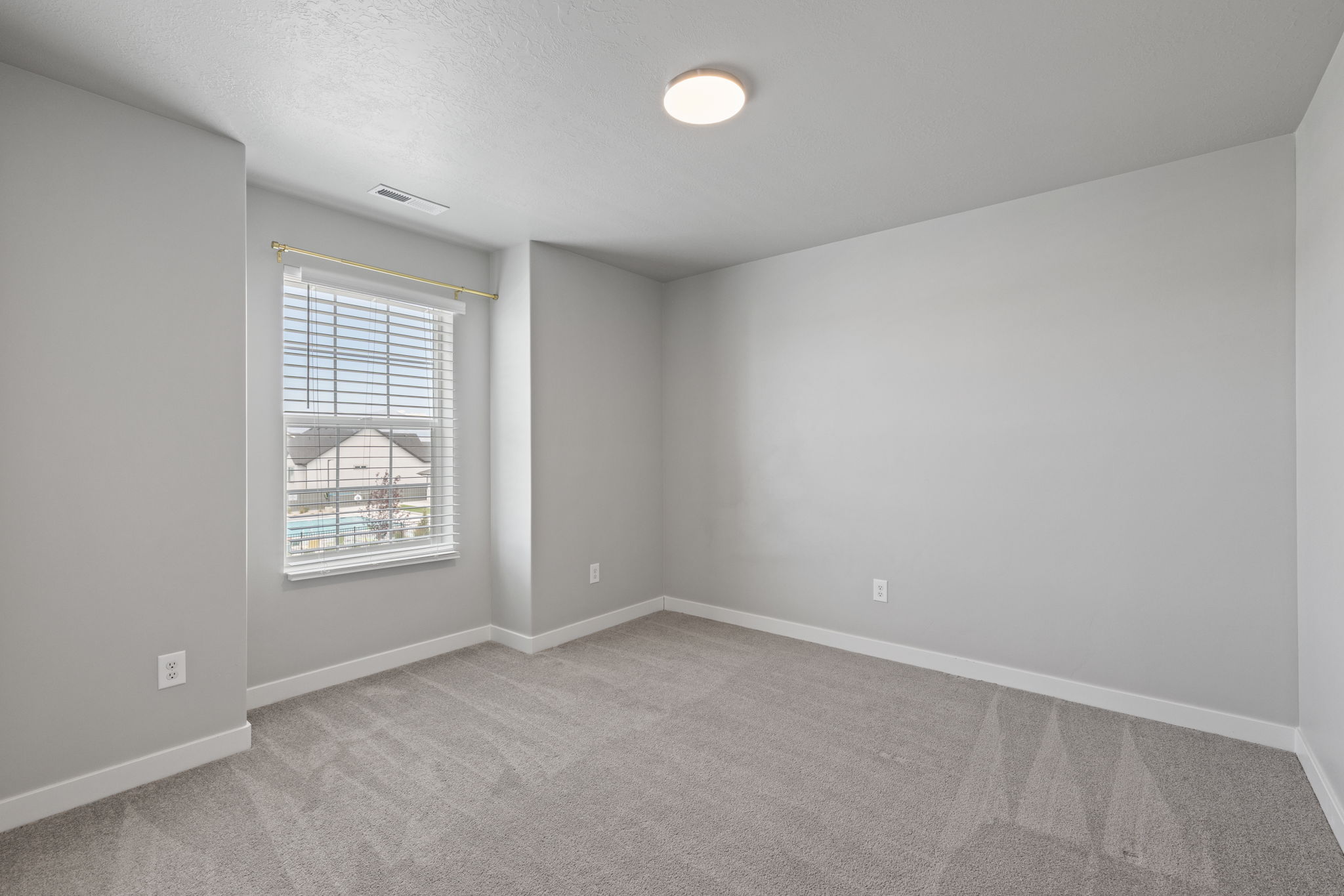 Carpeted room with a double-hung window featuring horizontal blinds