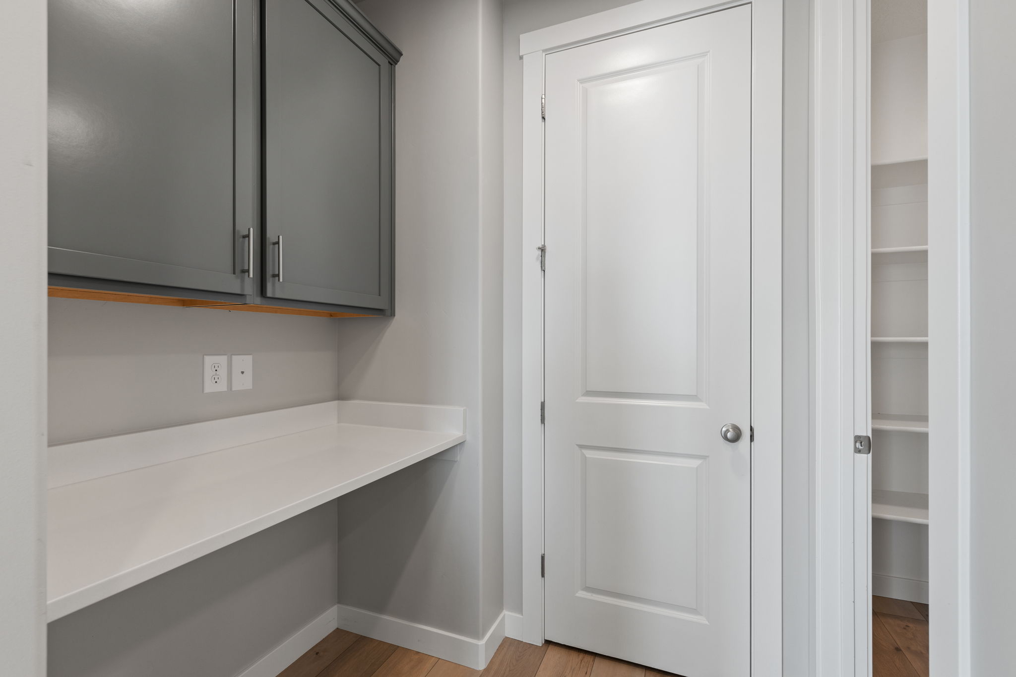 Built-in desk with a white countertop and gray cabinetry
