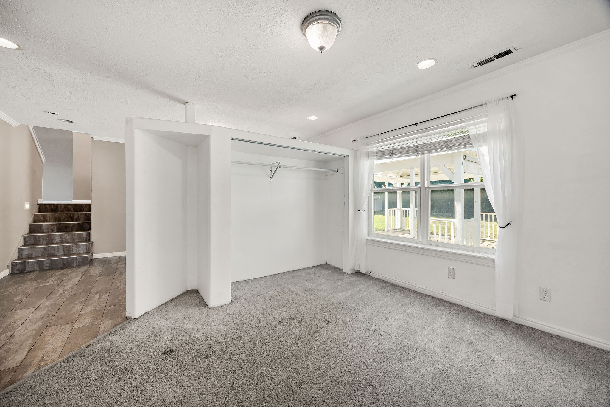 Bright room featuring neutral carpeting, a large window, recessed lighting, and an open closet space