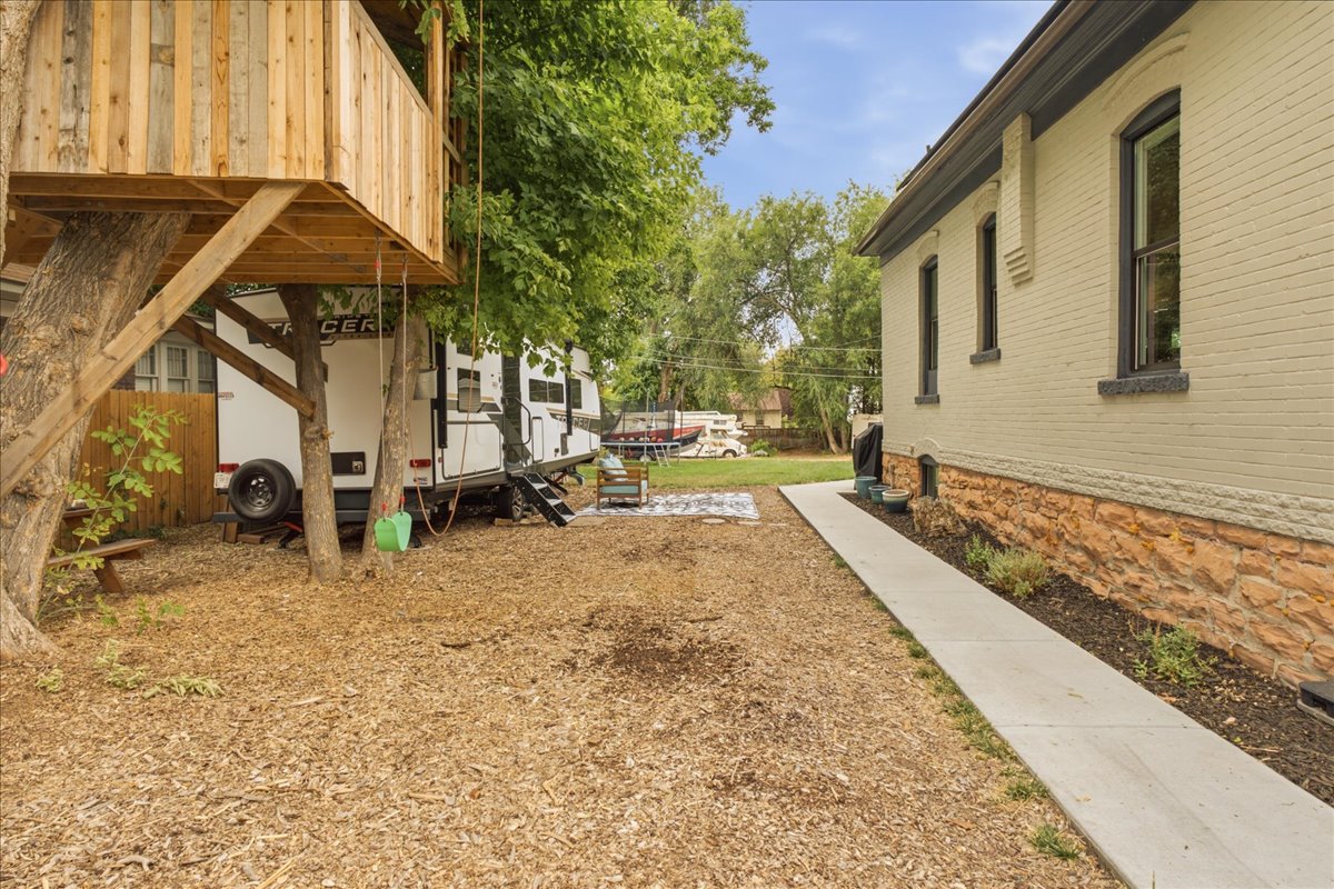 Exterior brick and stone foundation featuring multiple windows with dark trim, accompanied by a concrete pathway and wood chip ground cover