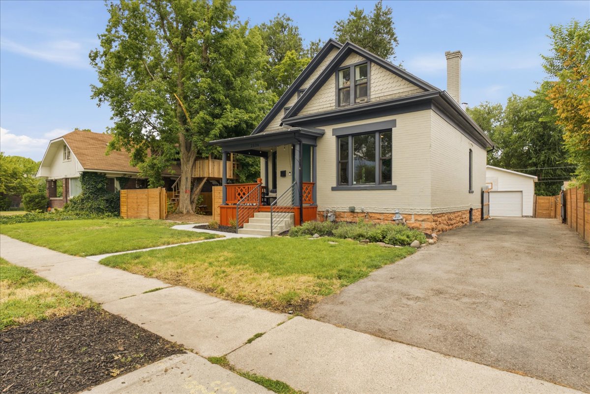 Crafted exterior featuring painted brick, dark trim accents, and a covered front porch with red-stained railings