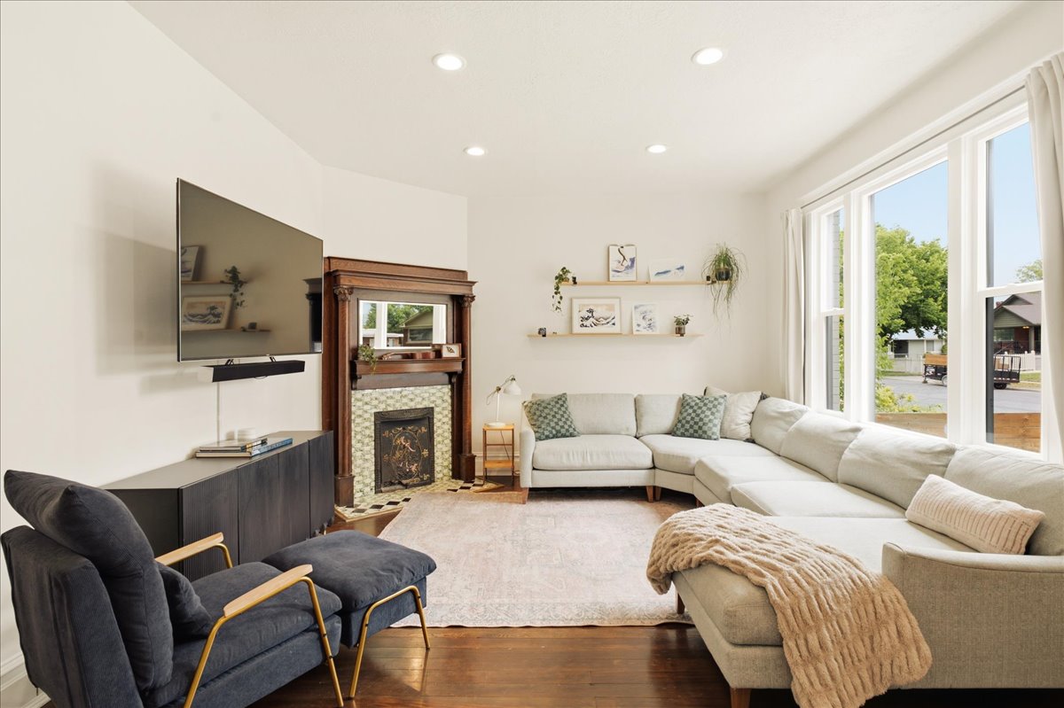 Living area featuring wood-finish flooring, recessed lighting, and large windows with white trim
