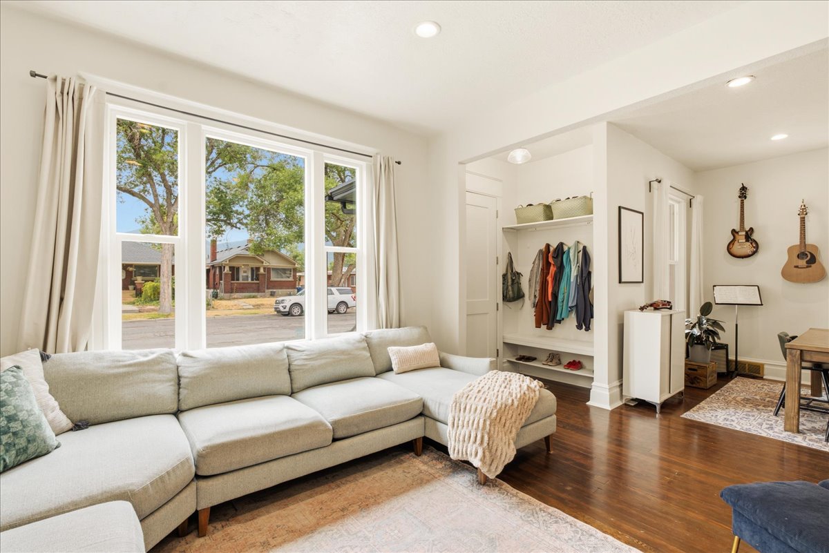 Bright living area featuring a large multi-pane window with white trim, recessed lighting, wood-finish flooring, and a built-in entryway organizer