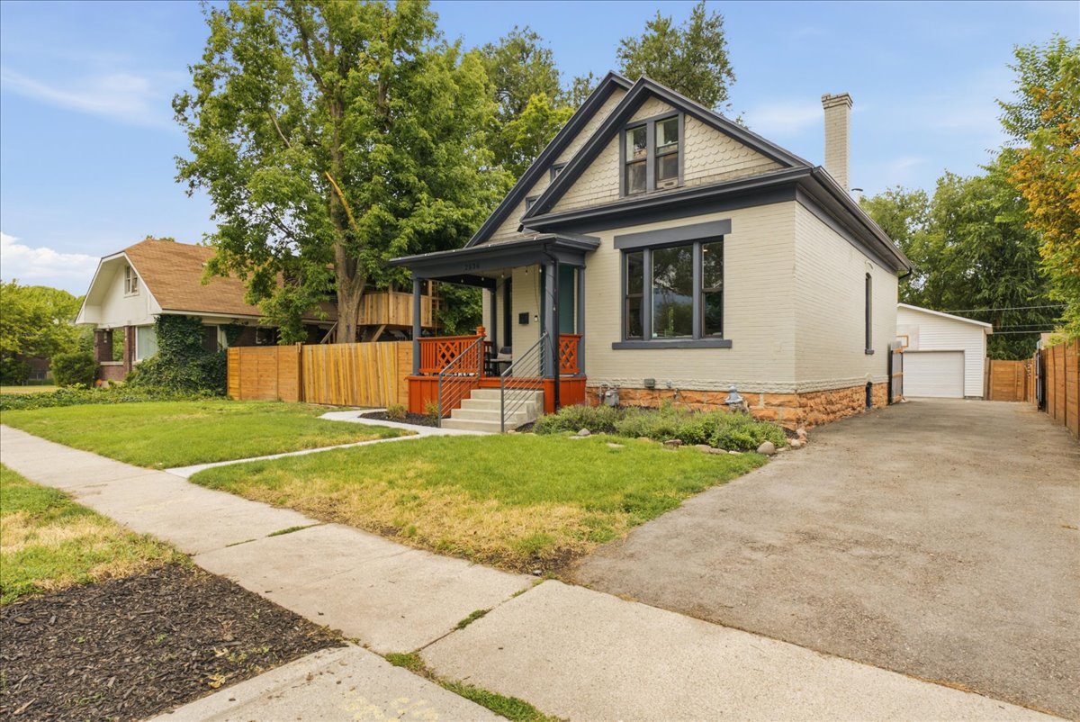 Charming traditional architecture featuring light-colored brick siding, a dark trim accent, and an attic dormer window