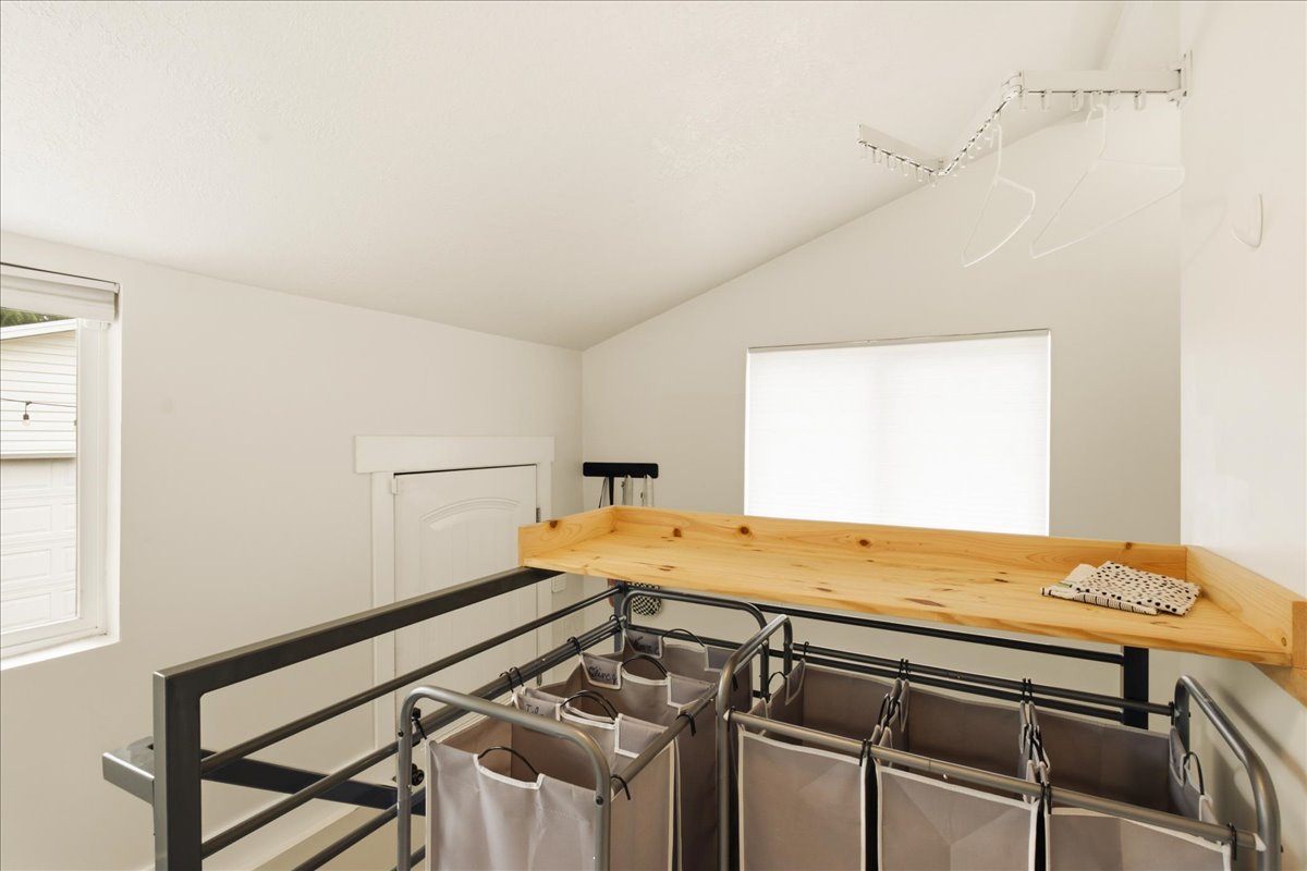 Bright loft space featuring a vaulted ceiling and an integrated wood-finish countertop