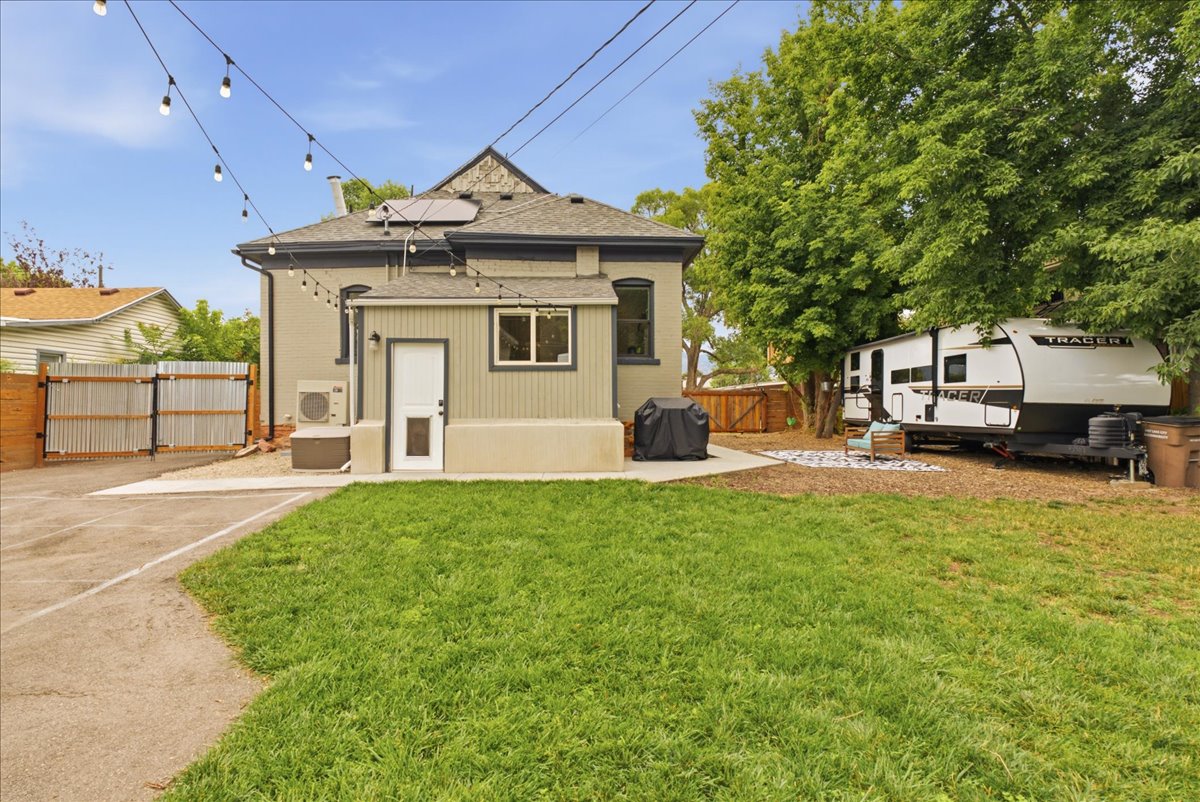 Expansive backyard featuring a lush lawn, concrete patio, and mature trees