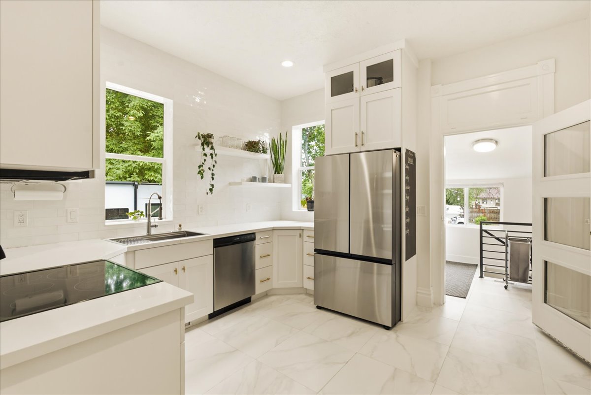 Modern kitchen featuring white cabinetry, stainless steel appliances, a built-in cooktop, and a subway tile backsplash