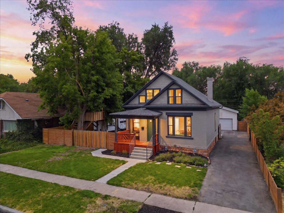 Charming residence featuring a covered front porch with a dark railing and red-toned wood accents
