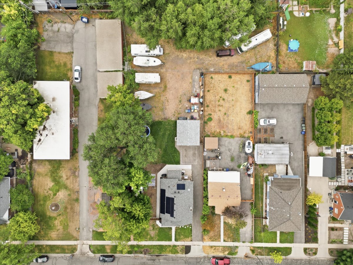 Aerial perspective showcasing multiple residential properties, mature trees, and paved streets