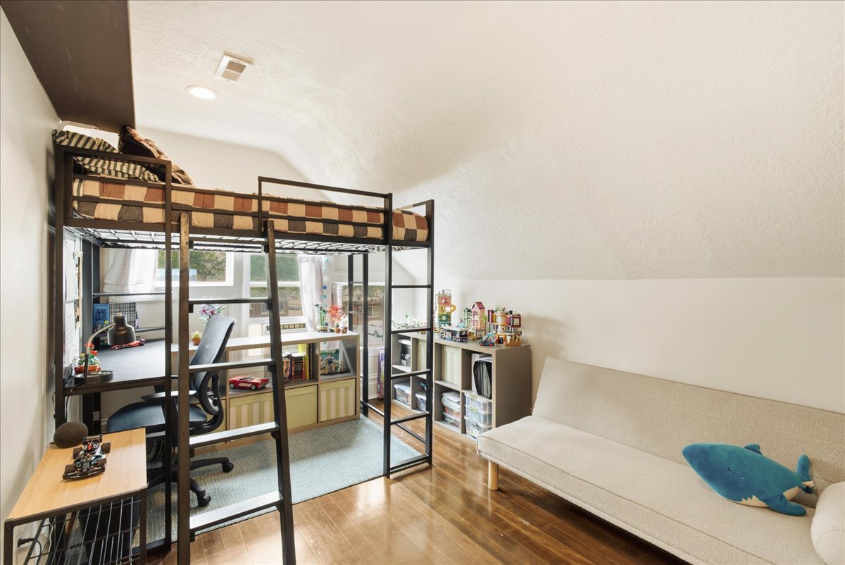Loft-style bed frame with an integrated desk area, multiple windows, recessed lighting, and wood-finish flooring