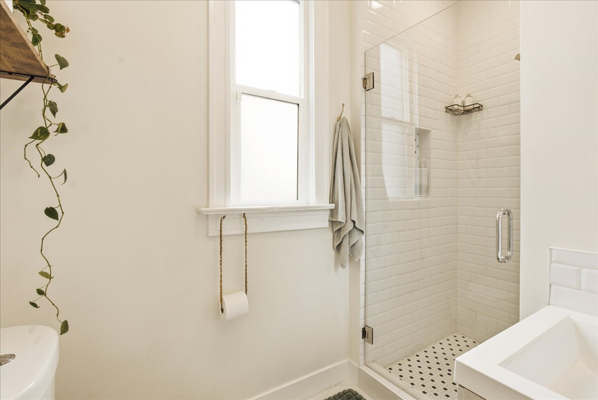 Glass-enclosed shower featuring white subway tile surround and a contrasting penny tile floor
