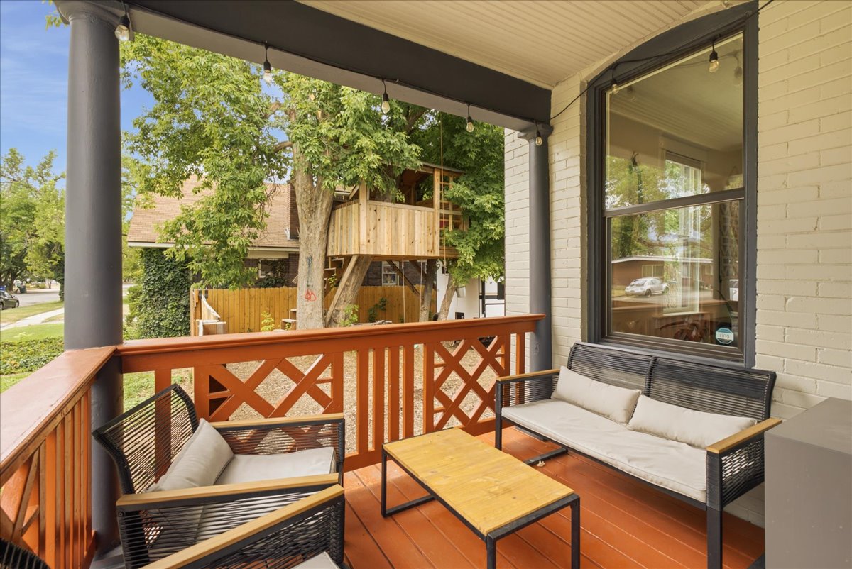 Covered porch featuring painted wood flooring and a decorative wood railing