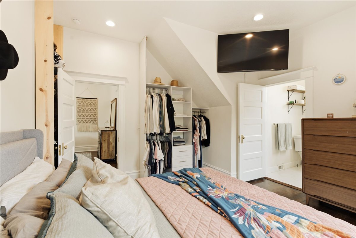 Attic space with built-in open shelving, recessed lighting, wood-finish flooring, and a flat-panel television