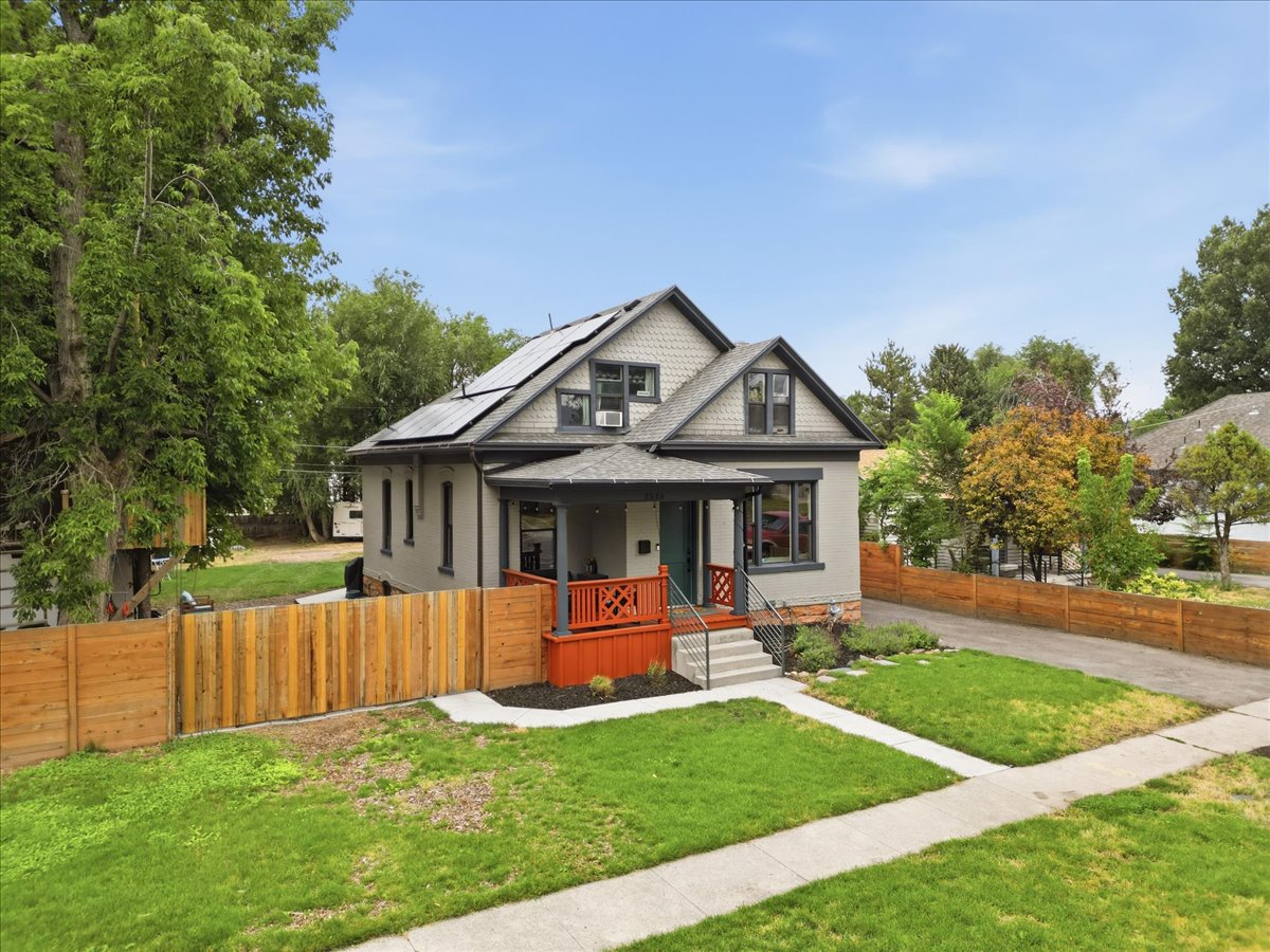 Two-story residence featuring a covered front porch, an asphalt shingle roof with solar panels, and a gabled dormer