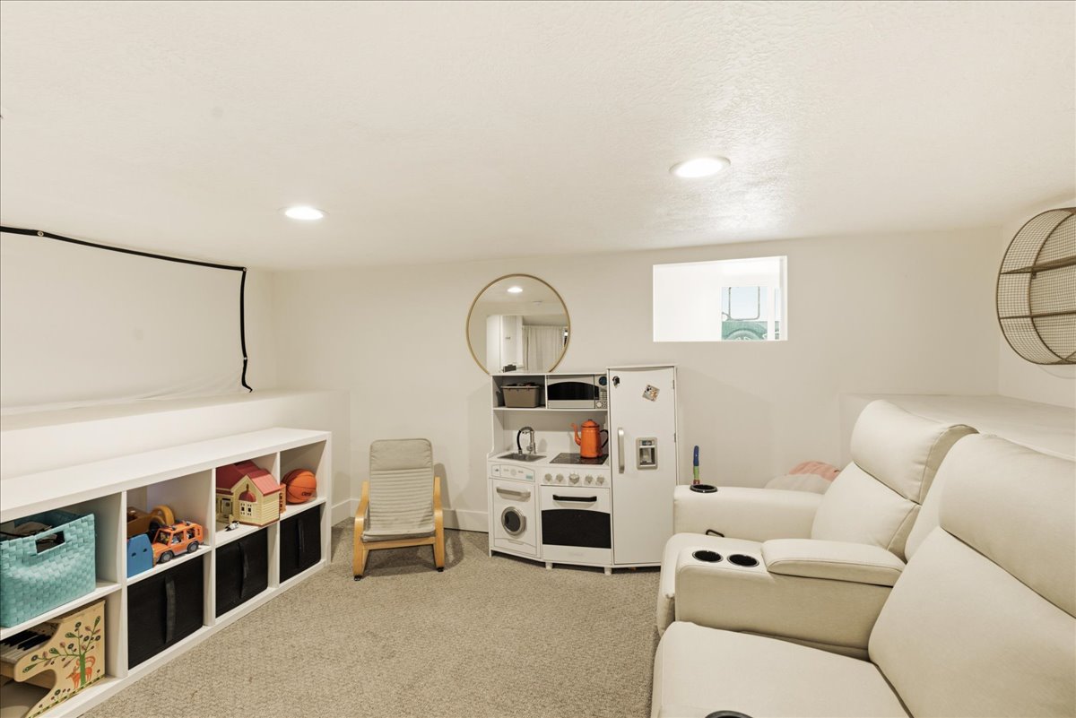 Carpeted recreational room featuring recessed lighting, a built-in storage unit with cubbies, and a small rectangular window