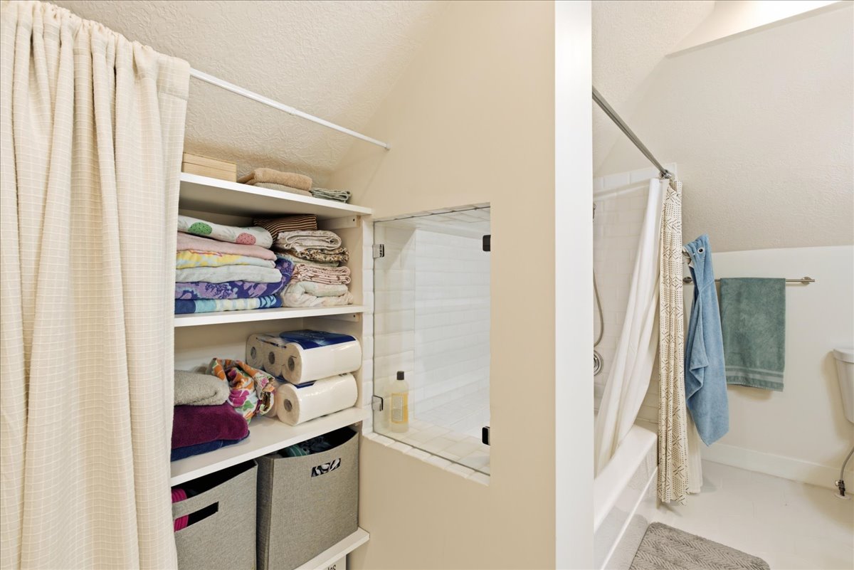 Built-in shelving unit with multiple storage compartments, accompanied by a recessed wall cabinet with a glass door