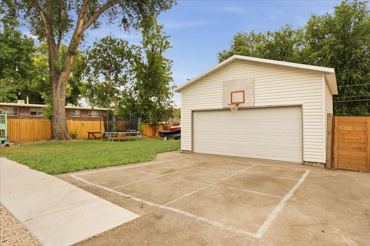 Detached garage with horizontal siding, a single overhead door, and an attached basketball hoop